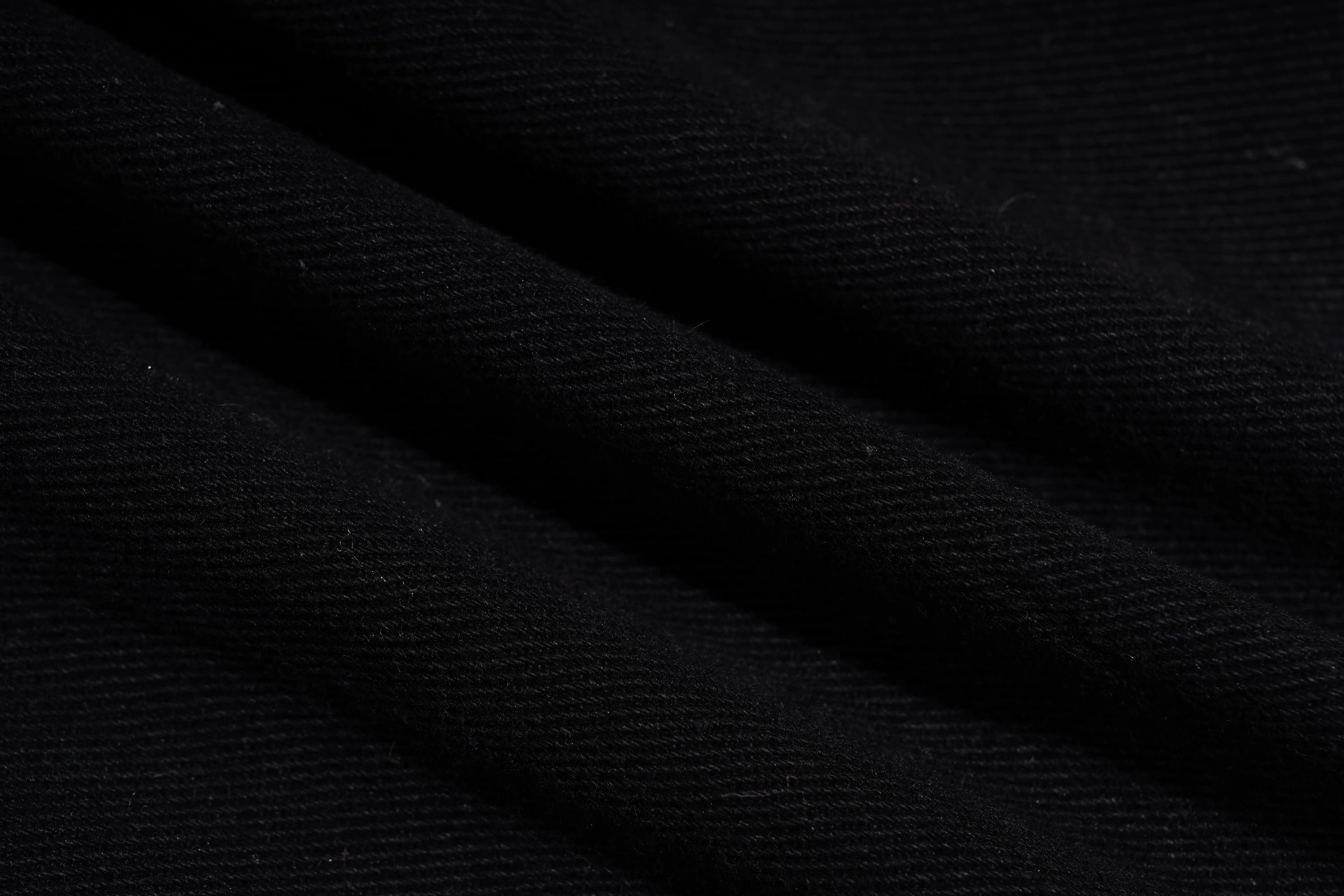 A close-up of dark charcoal gray or black textured fabric with diagonal folds showing a fine ribbed weave. TCH Rhinestone Butterfly & Dragon Graphic Black Cargo Shorts