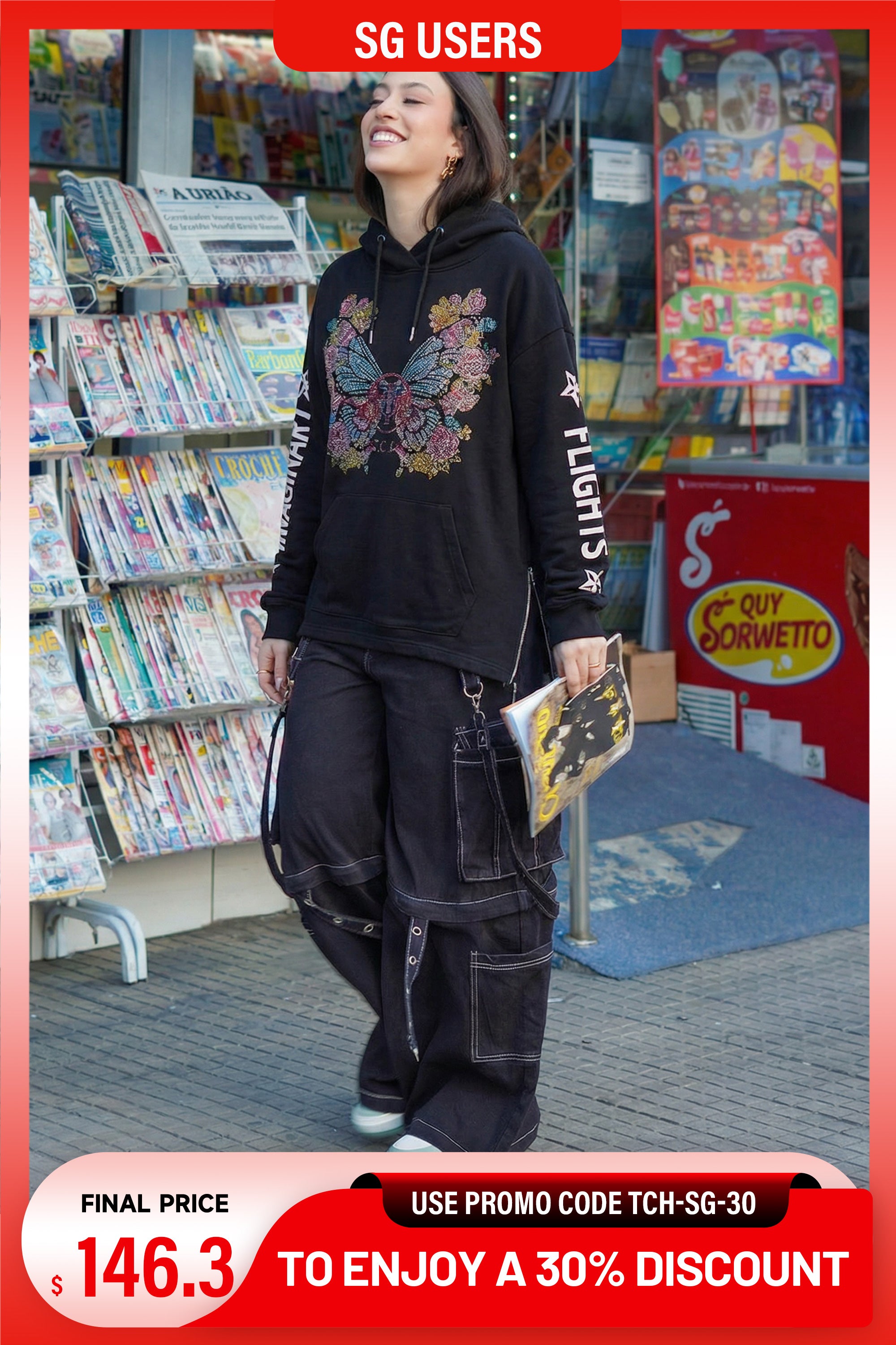 Person wearing a black hoodie with butterfly design in a store, with promotional text overlay. TCH Rhinestone Butterfly Elephant Hoodie