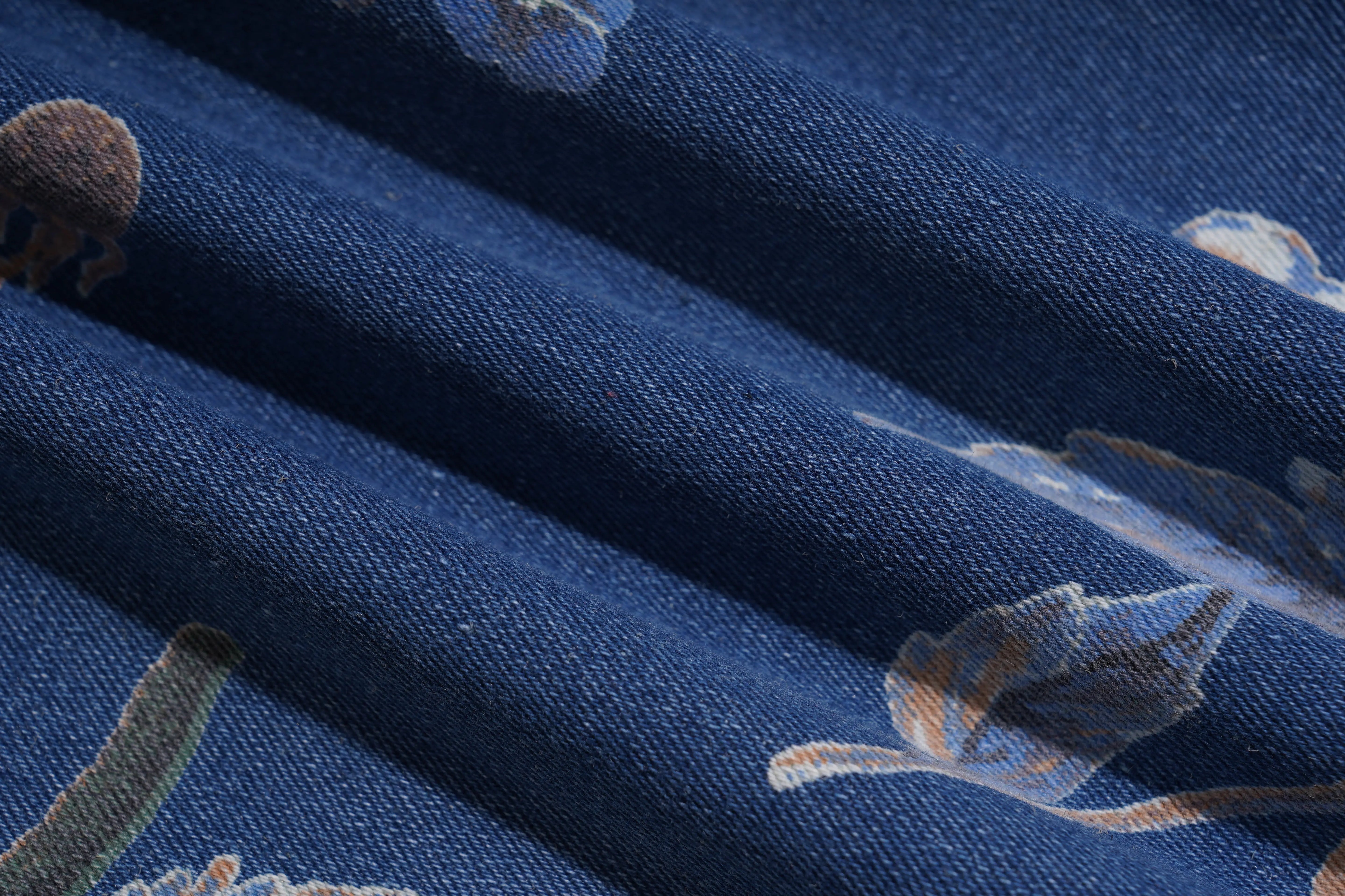 Close-up of blue fabric with embroidered designs, including a tiger and other elements. TCH Rhinestone Butterfly Floral Print Denim Jeans