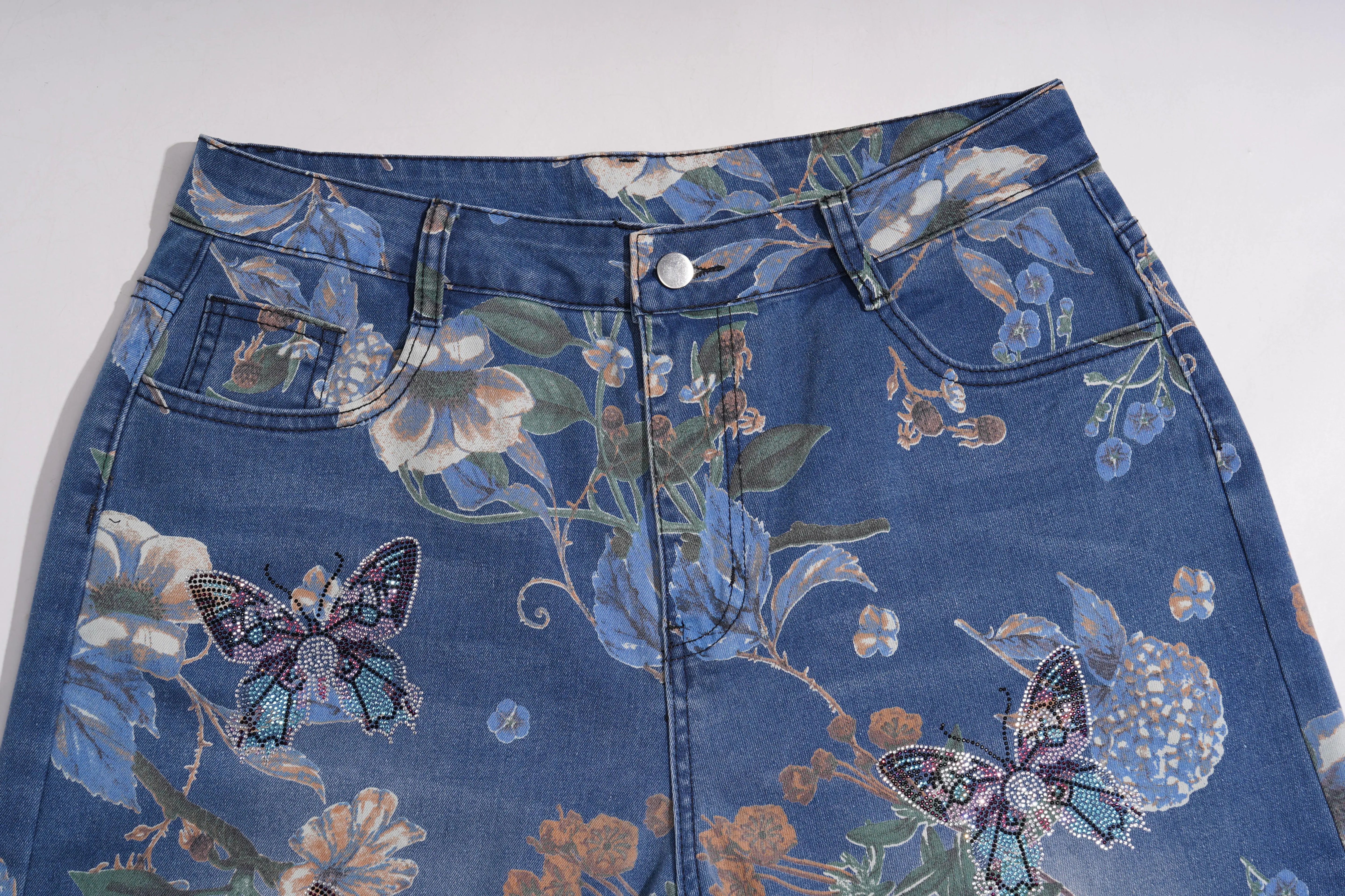 Blue denim shorts with floral and butterfly patterns on a white background, TCH Rhinestone Butterfly Floral Print Denim Jeans