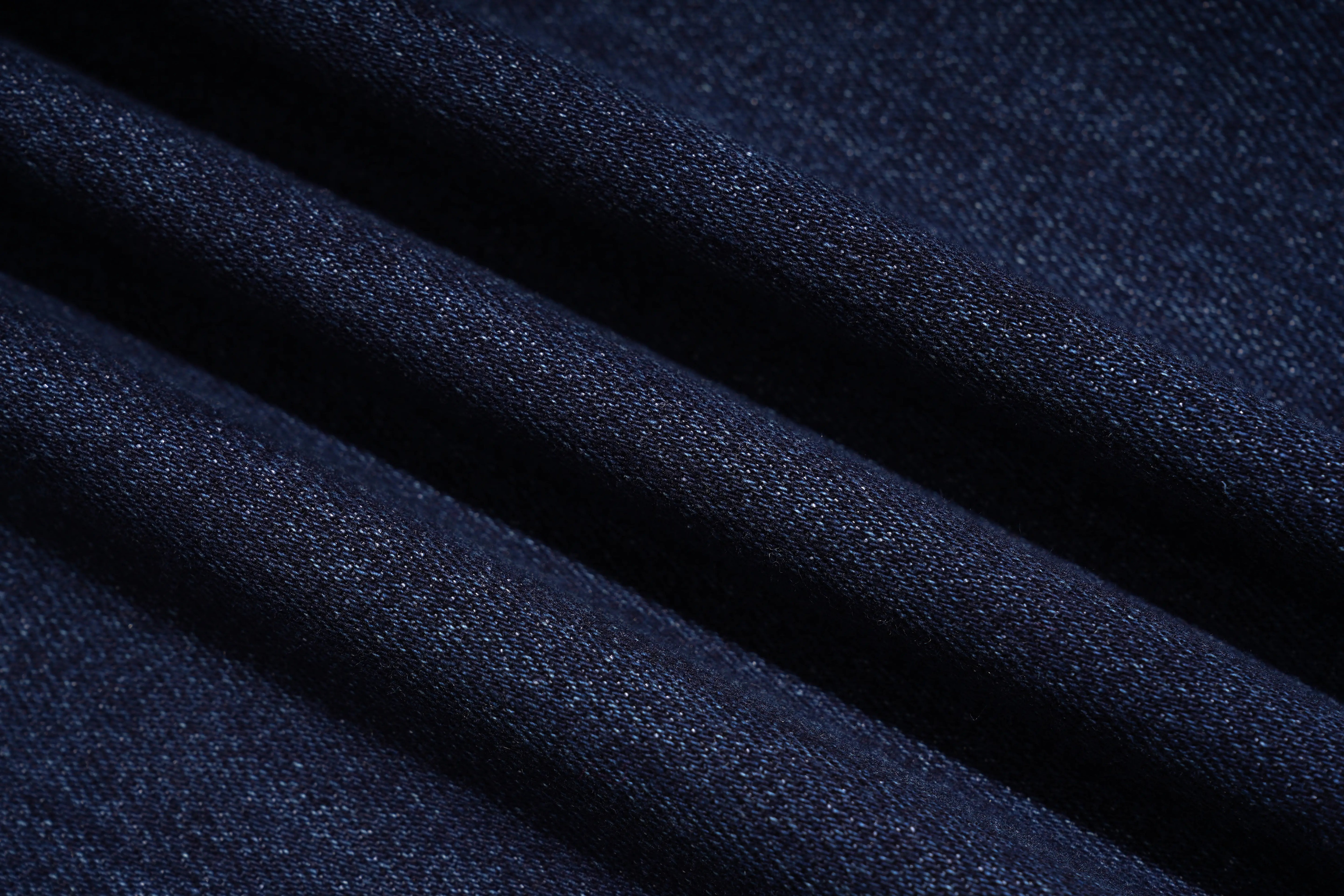 A close-up of dark navy blue fabric with soft diagonal folds showing a fine woven texture. TCH Rhinestone Butterfly Graphic Wide-Leg Jeans
