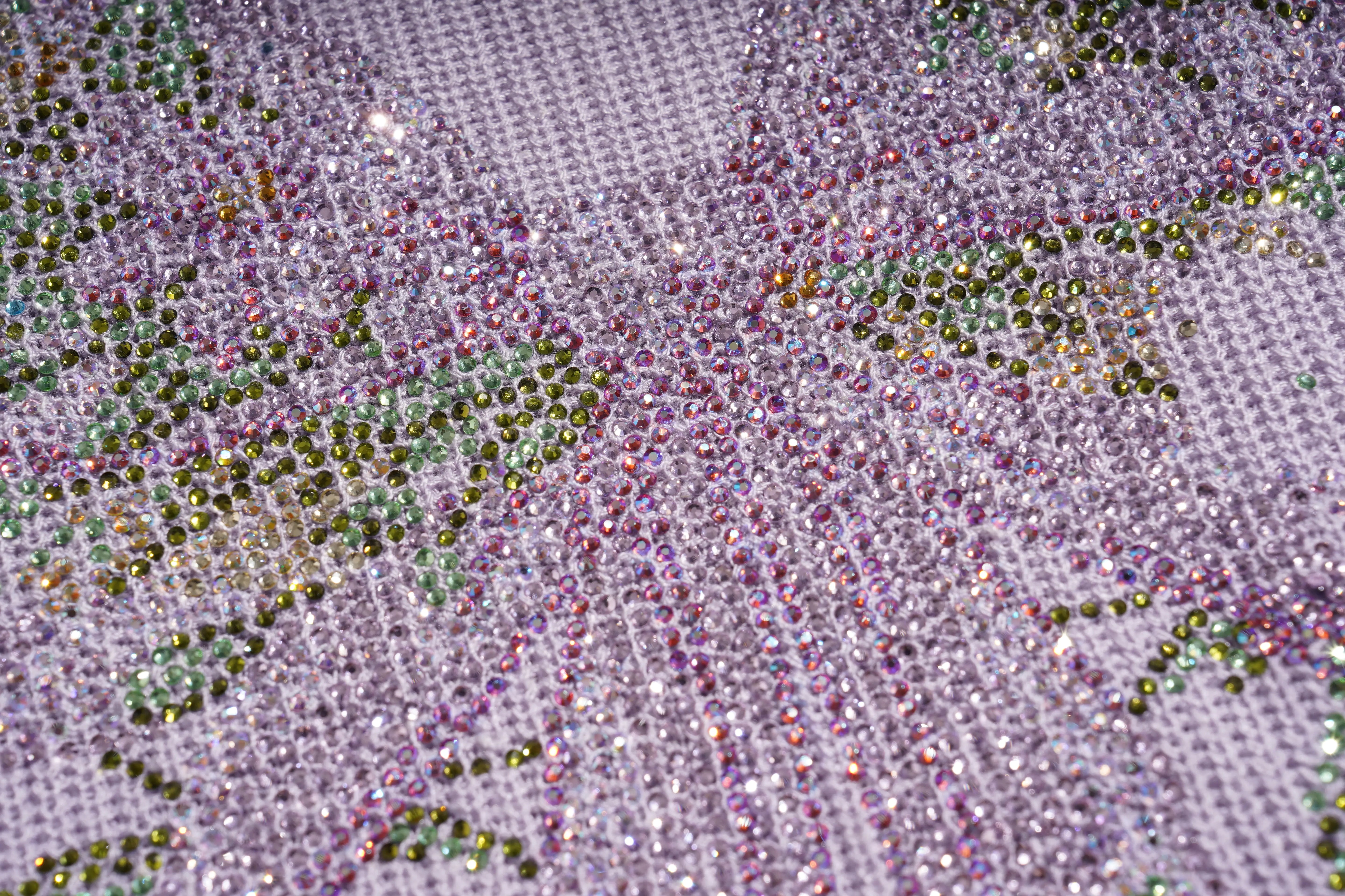 Close-up of a diamond painting canvas with iridescent rhinestones forming a butterfly design on a light purple mesh background. TCH Rhinestone Butterfly Knit Twist Top