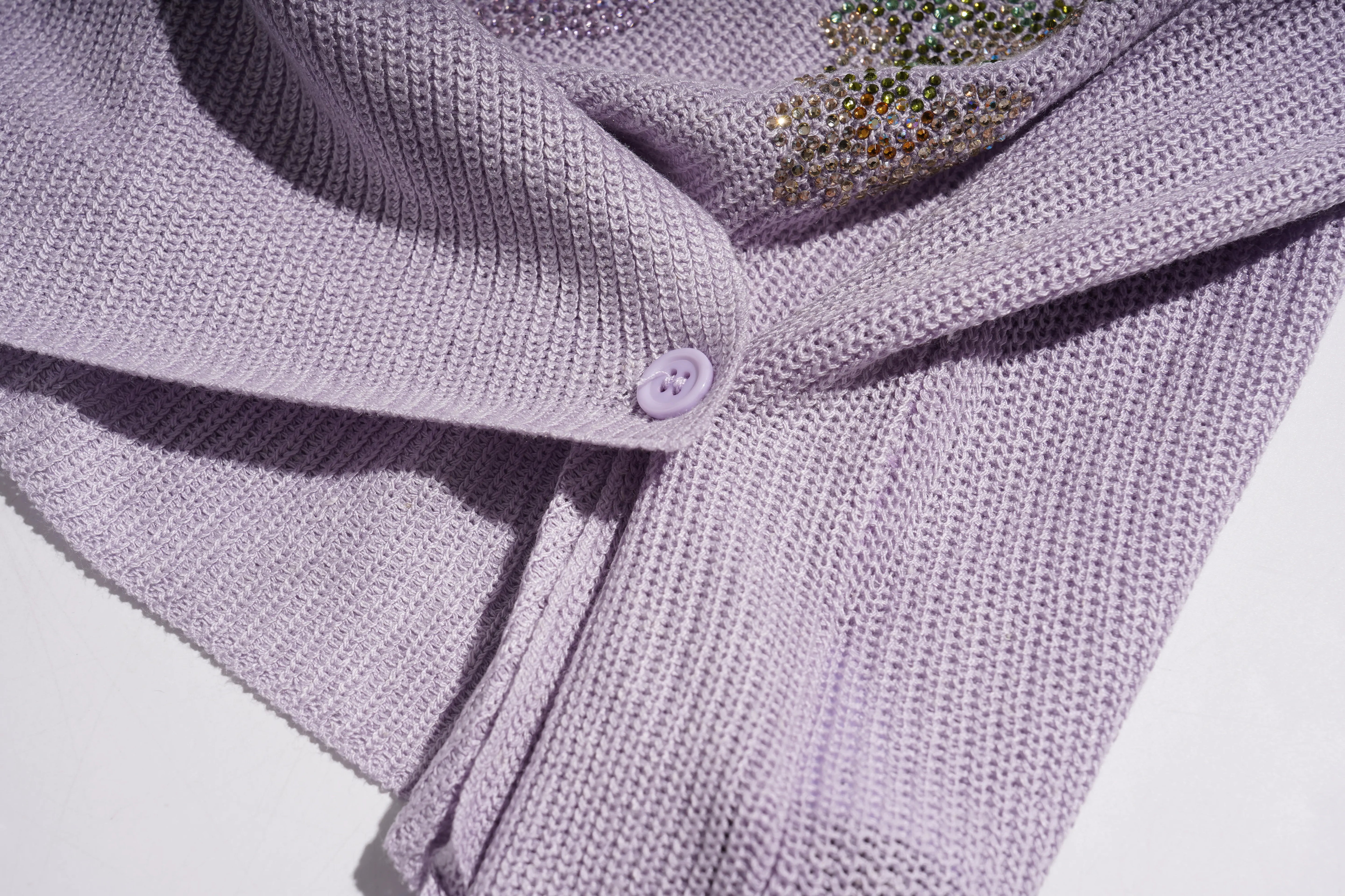 Close-up of a lavender knit cardigan featuring a matching button and a decorative multicolor crystal embellishment. TCH Rhinestone Butterfly Knit Twist Top