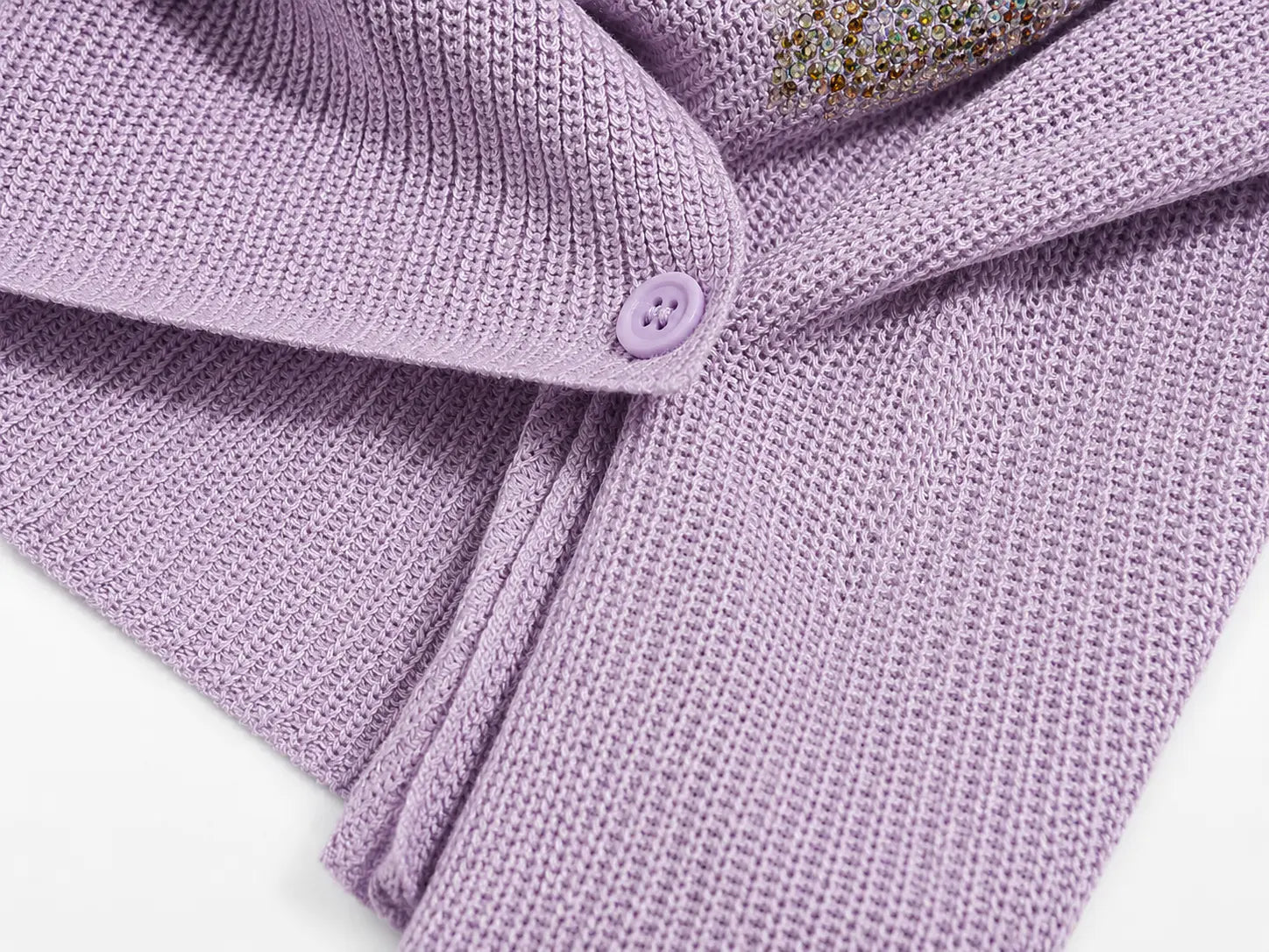 Close-up of a lavender purple knit cardigan or sweater with a matching button and a small decorative floral embellishment, shown on a white background. TCH Rhinestone Butterfly Knit Twist Top