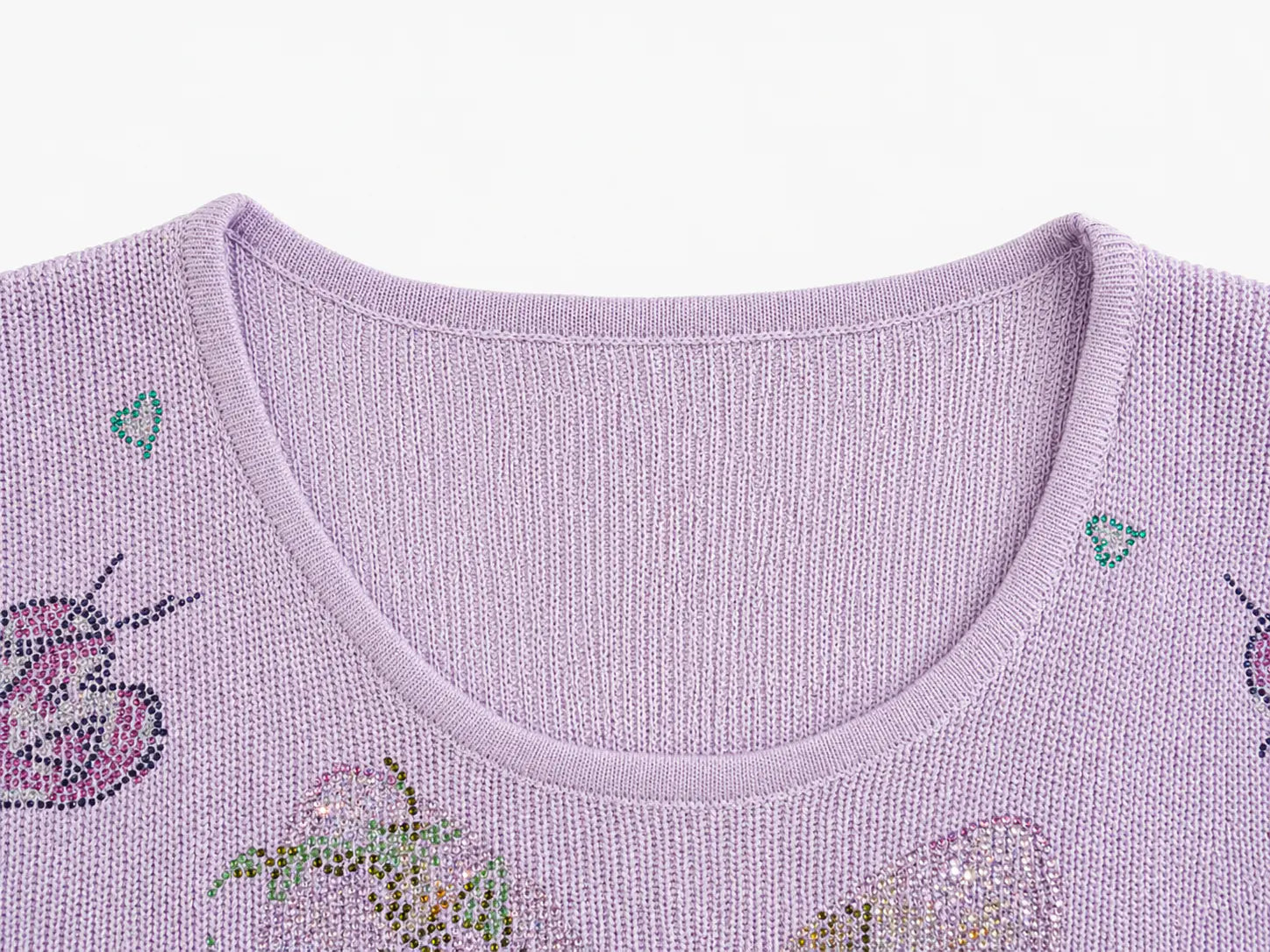 Close-up of a lavender knit sweater with butterfly and strawberry embellishments, showing the crew neckline and textured fabric against a white background. TCH Rhinestone Butterfly Knit Twist Top