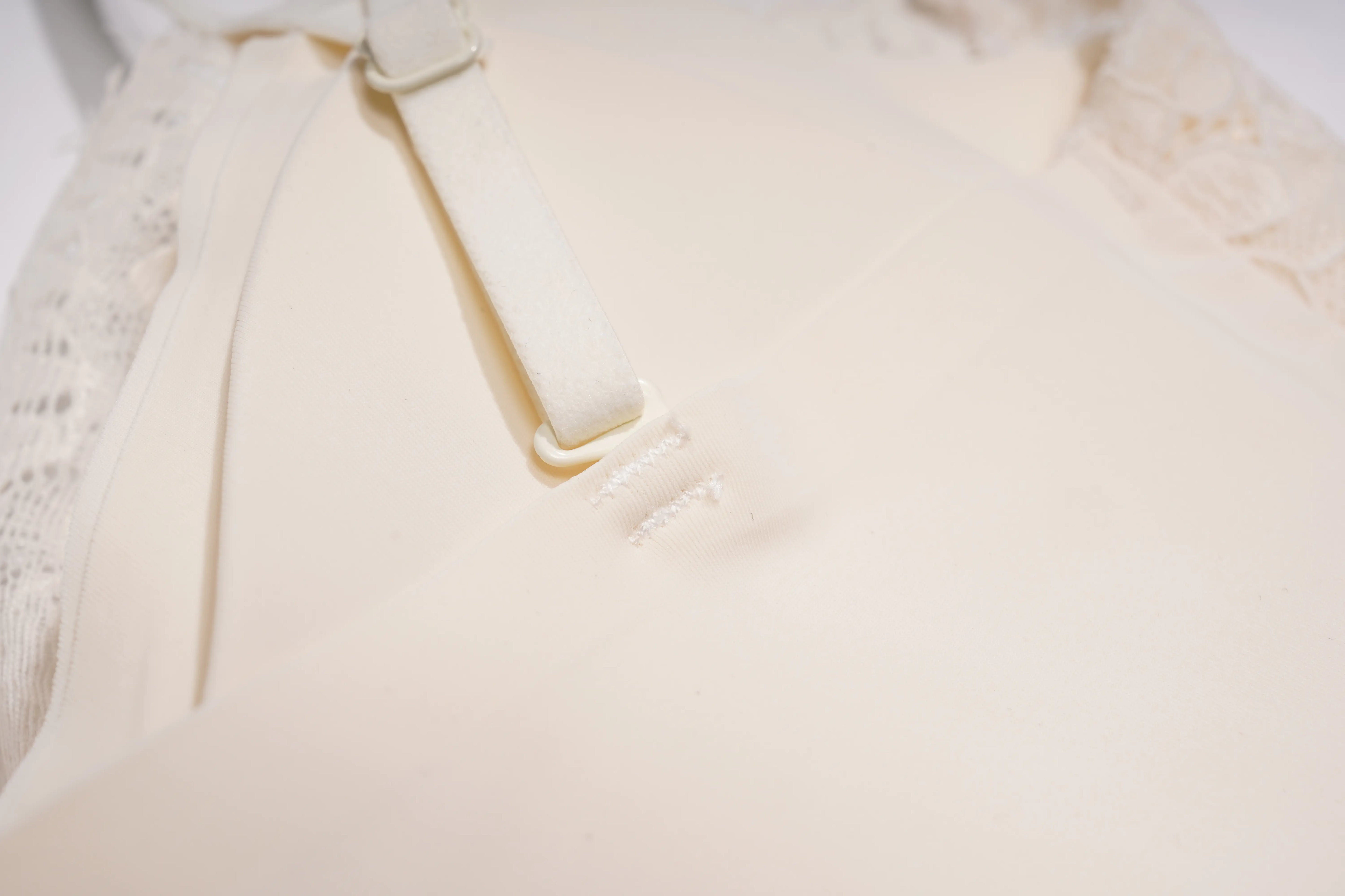 Close-up of a cream-colored bra strap and underband with delicate lace trim visible at the edges. TCH Rhinestone Butterfly Lace Cami Top