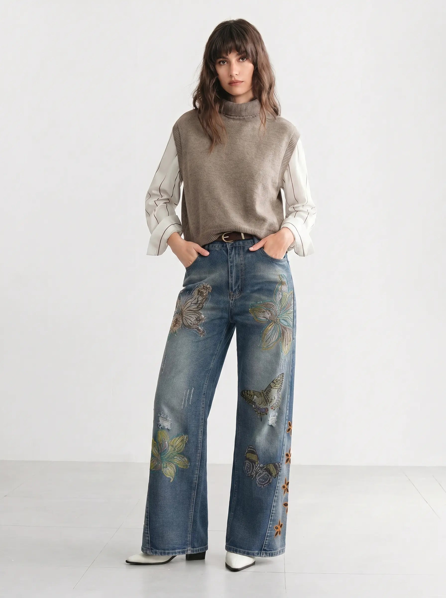 Woman wearing a gray turtleneck, white shirt, and blue jeans with floral embroidery on a white background, TCH Rhinestone Butterfly & Lily Distressed Denim Jeans