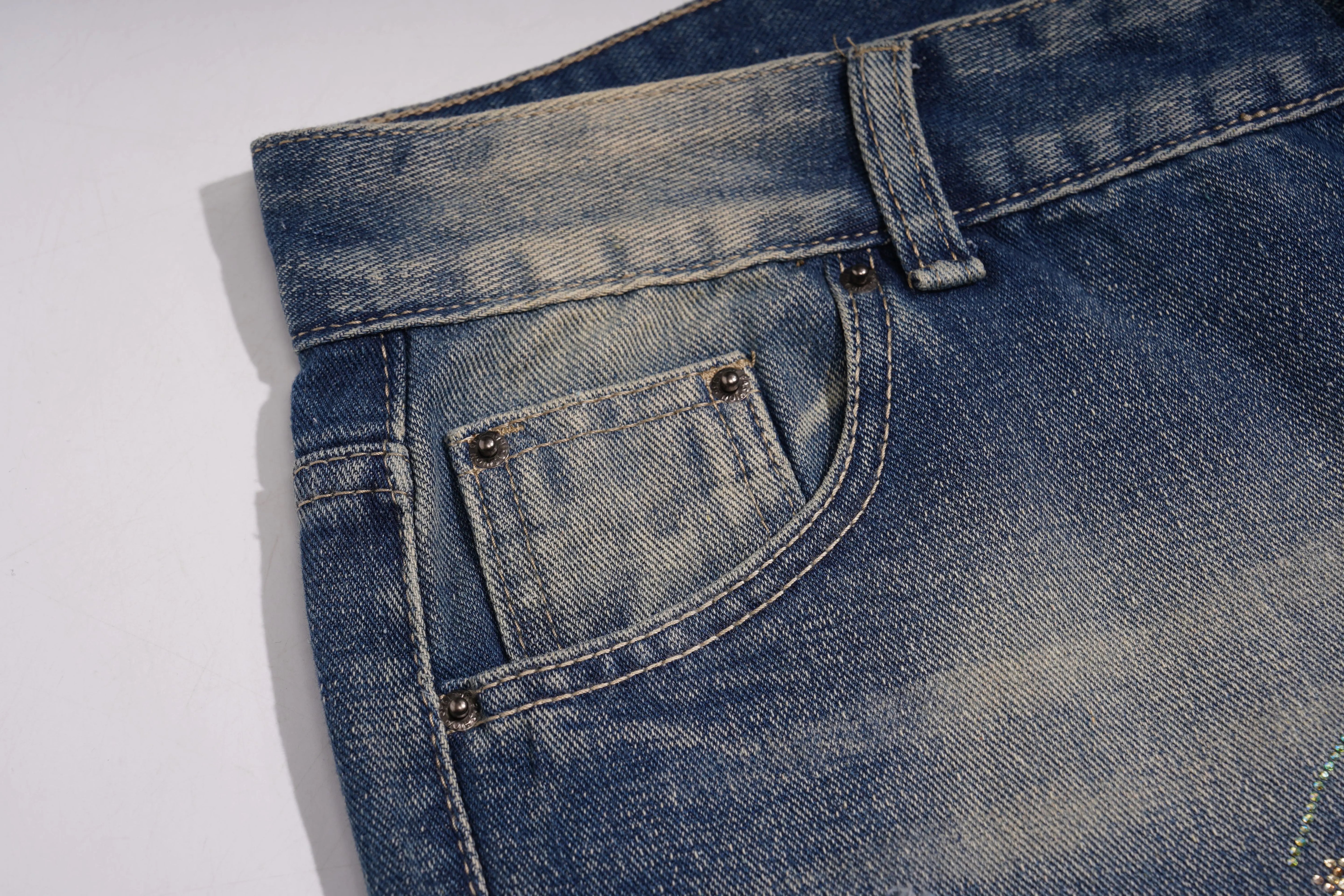 Close-up of blue denim jeans with a pocket on a white background, TCH Rhinestone Butterfly & Lily Distressed Denim Jeans