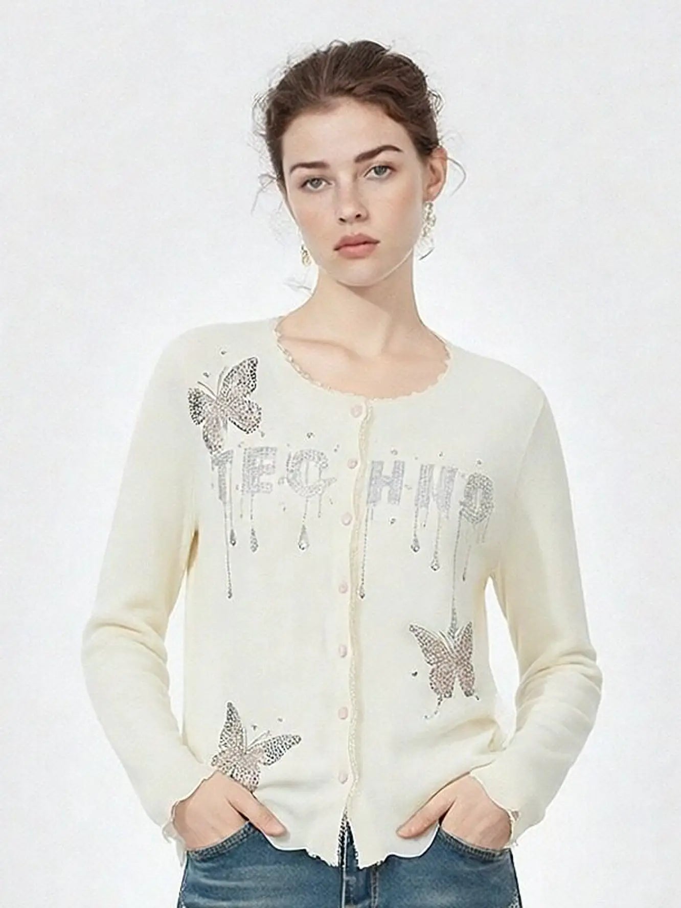 Woman wearing a cream cardigan with butterfly designs and 'TECH' text on a white background, TCH Rhinestone Butterfly Logo Knit Cardigan