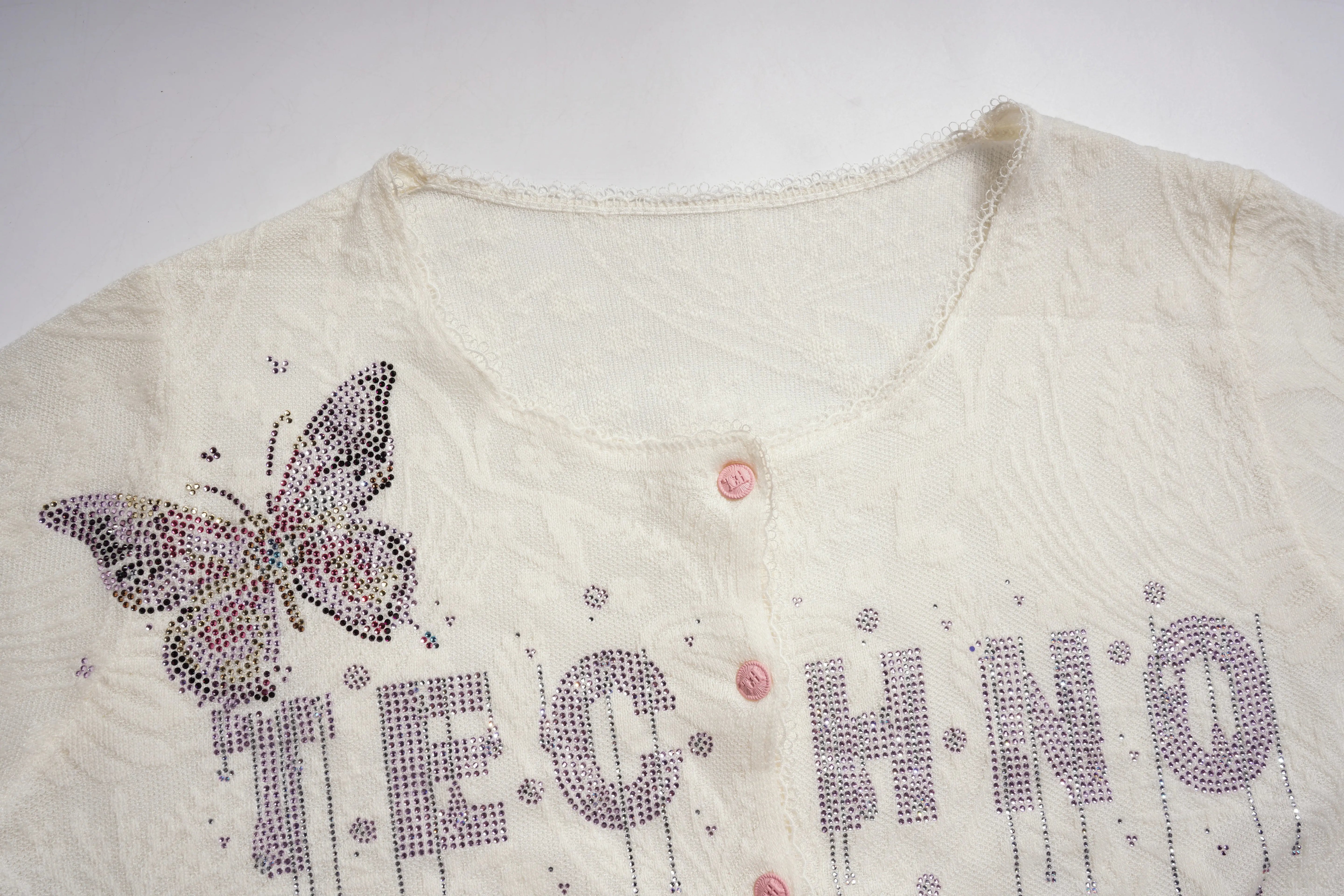 White garment with butterfly design and 'F.E.C. HINO' text on a white background, TCH Rhinestone Butterfly Logo Knit Cardigan