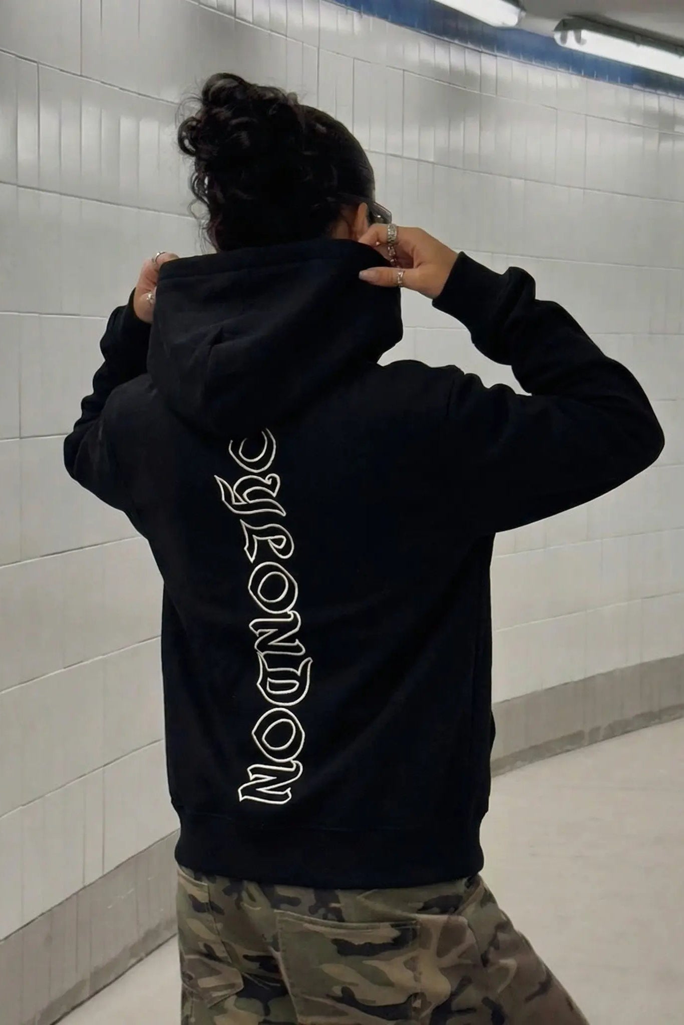 Person wearing a black hoodie with text on the back in an indoor setting. TCH Rhinestone Butterfly & Peony Embroidered Hoodie