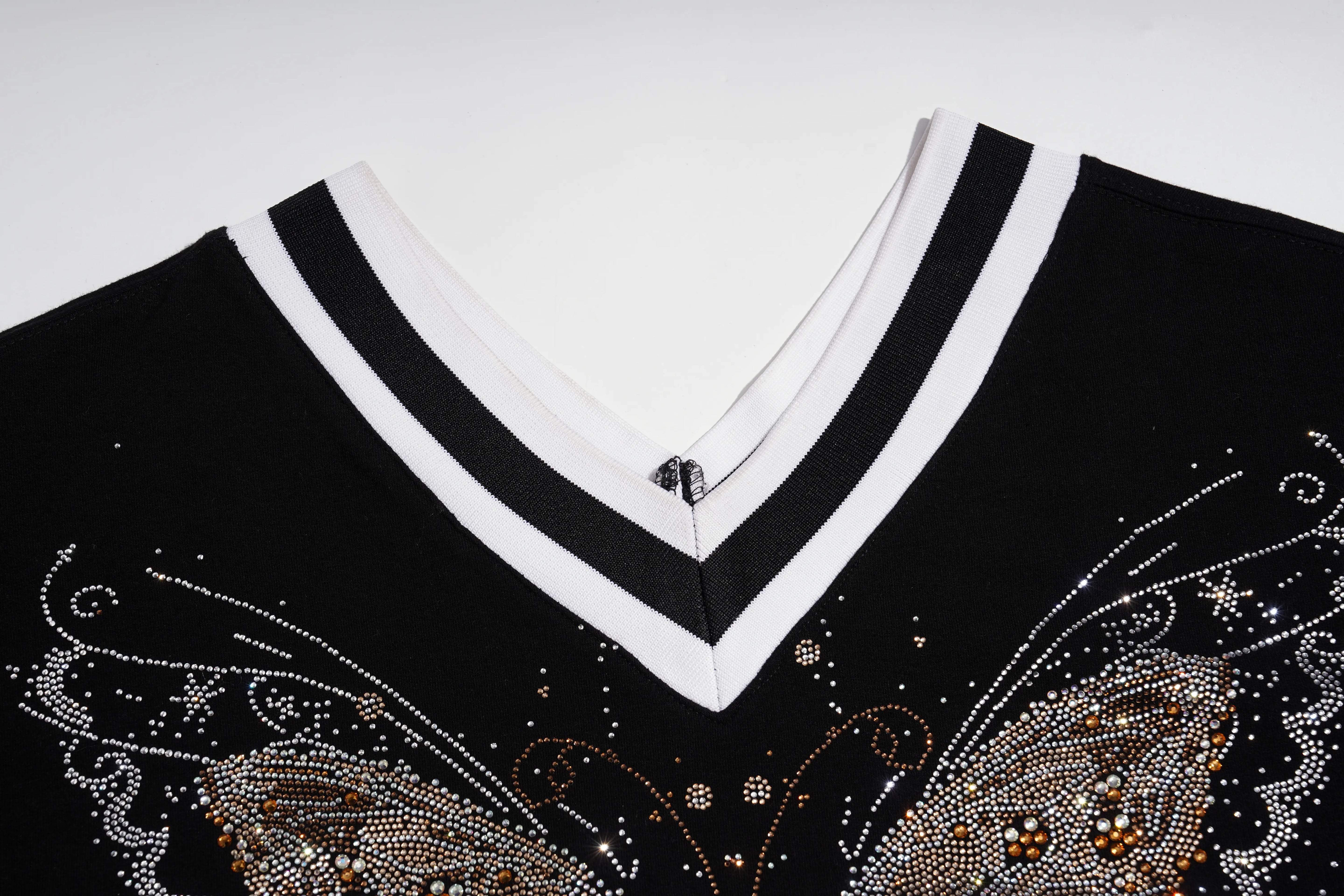 Close-up of a black V-neck top with a white double-striped collar and rhinestone butterfly embellishments on the chest. TCH Rhinestone Butterfly V-Neck Oversized Baseball T-Shirt