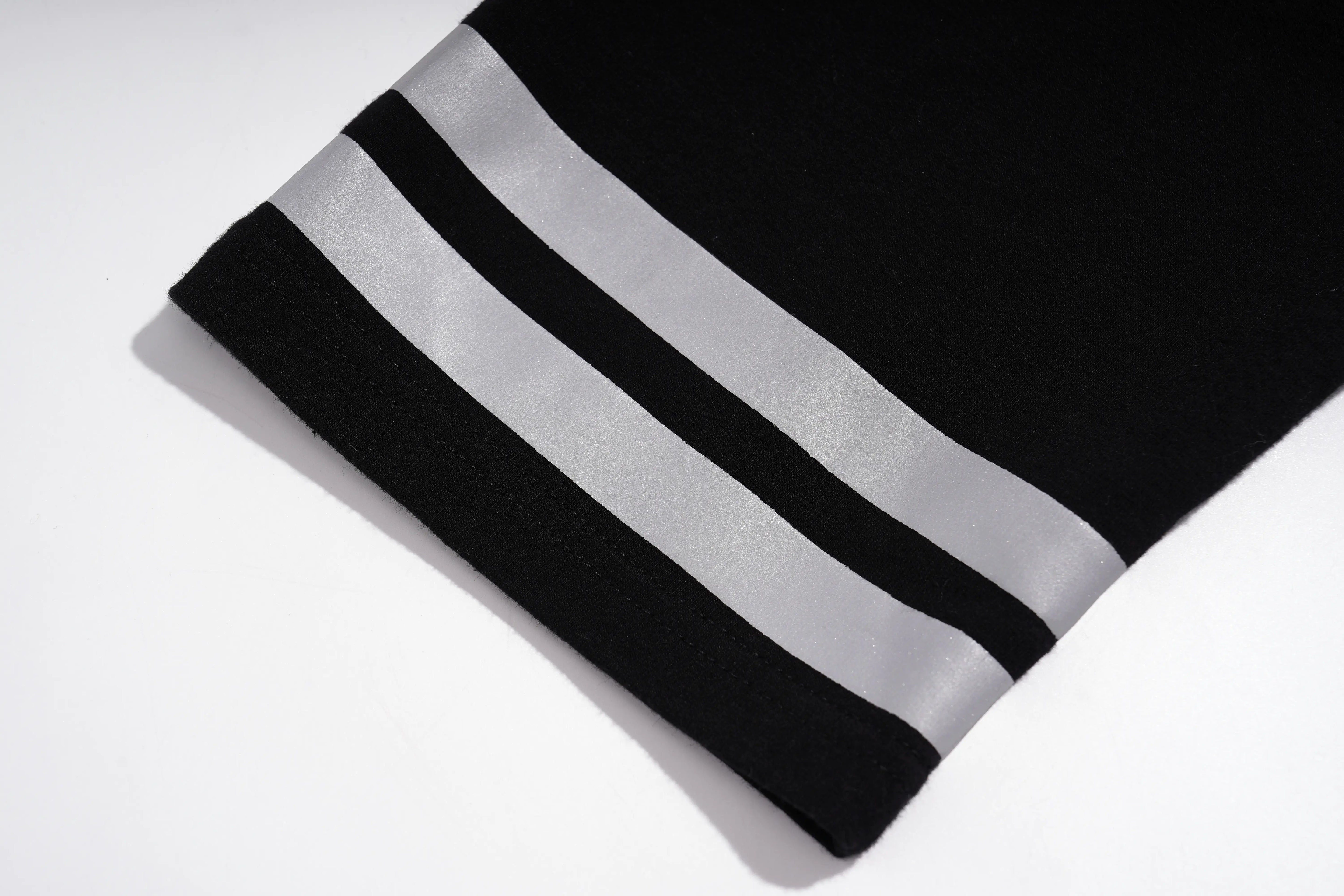 A close-up of a black knit sleeve or cuff with two wide silver stripes near the edge, photographed on a white background. TCH Rhinestone Butterfly V-Neck Oversized Baseball T-Shirt