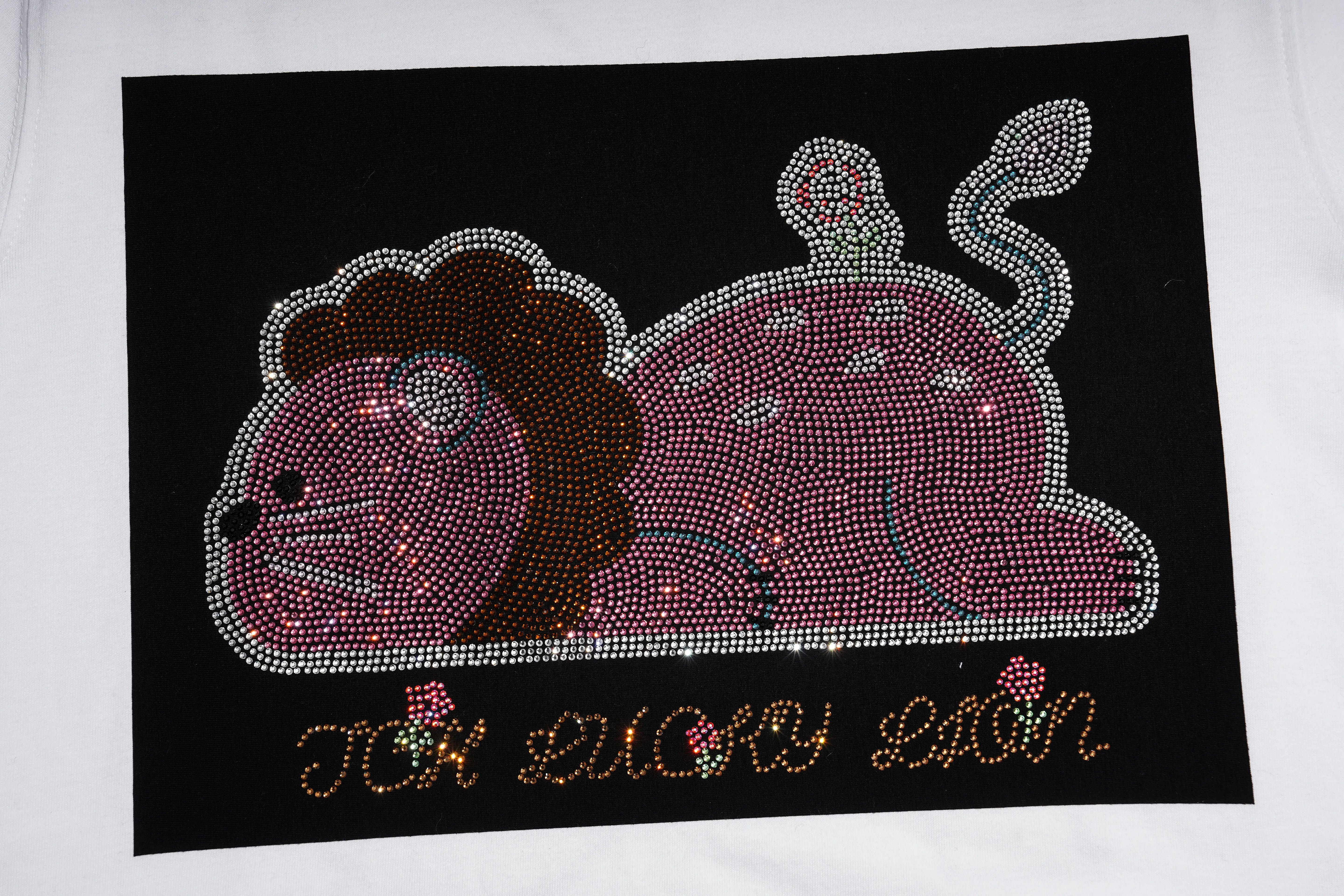 A rhinestone-covered lion design on a black rectangular background, placed on a white surface. The lion is pink and purple with a dark brown mane, and the text 'JCK LUCKY LION' is written below in gold-toned rhinestones with small pink floral accents. TCH Rhinestone Cartoon Pig Graphic Baseball T-Shirt