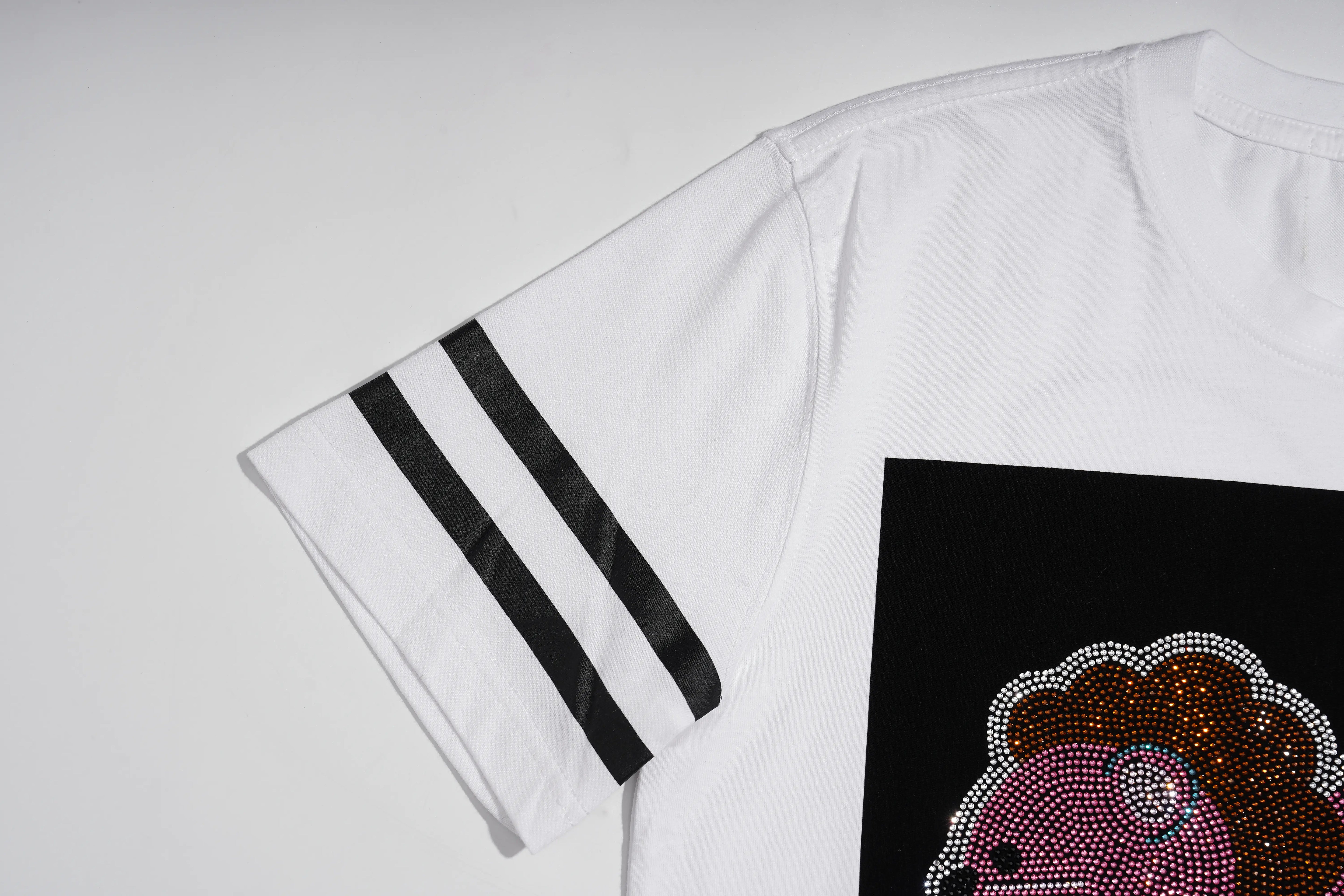 White short-sleeve t-shirt with three black stripes on the sleeve and a black graphic panel on the front featuring a pink rhinestone lion face. TCH Rhinestone Cartoon Pig Graphic Baseball T-Shirt