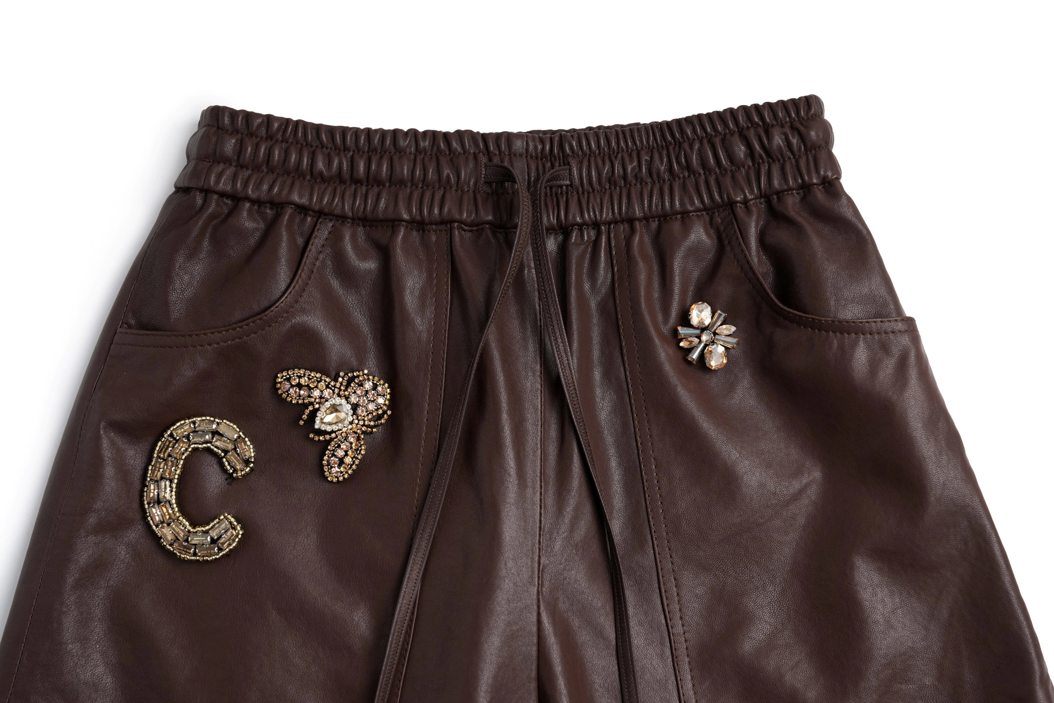 Brown leather pants with decorative pins on a white background, TCH Rhinestone Charm Faux Leather Brown Shorts