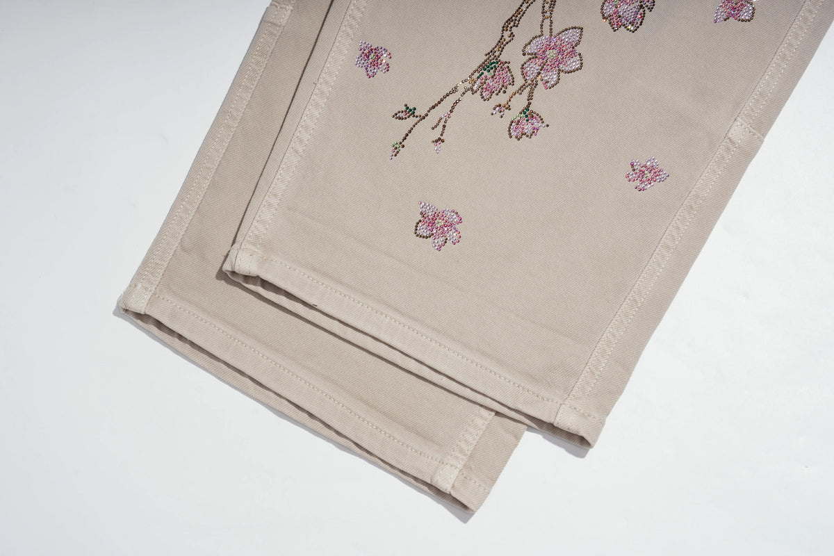 A folded beige fabric napkin or table linen with pink cherry blossom embroidery, displayed on a clean white background. TCH Rhinestone Cherry Blossom Straight-Leg Jeans