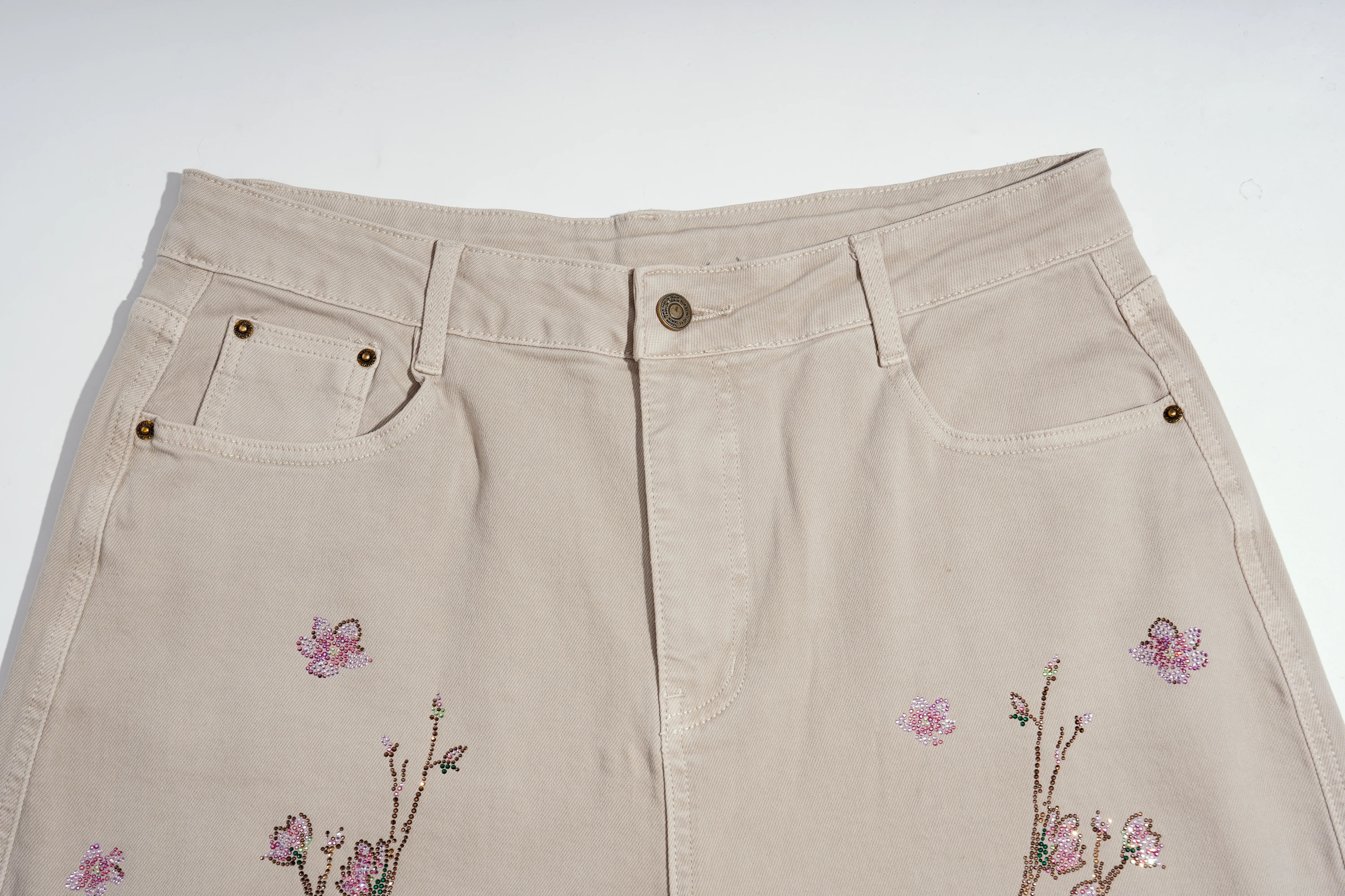 Beige denim skirt with pink floral embroidery and sequin accents on the front, shown against a plain white background. TCH Rhinestone Cherry Blossom Straight-Leg Jeans