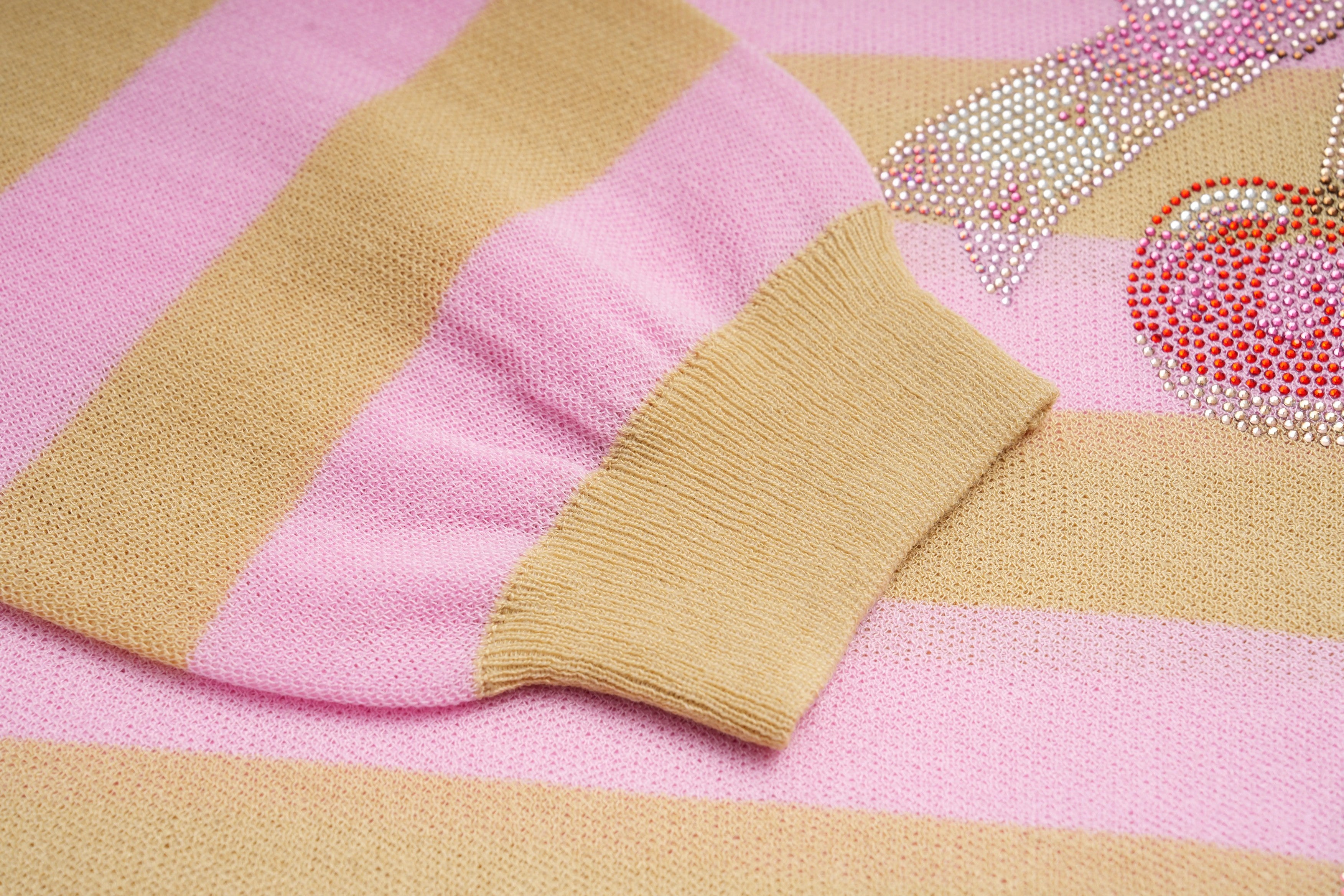 Close-up of a pink and beige striped fabric with decorative elements. TCH Rhinestone Cherry Bow Pink Striped Polo Long Sleeve Shirt