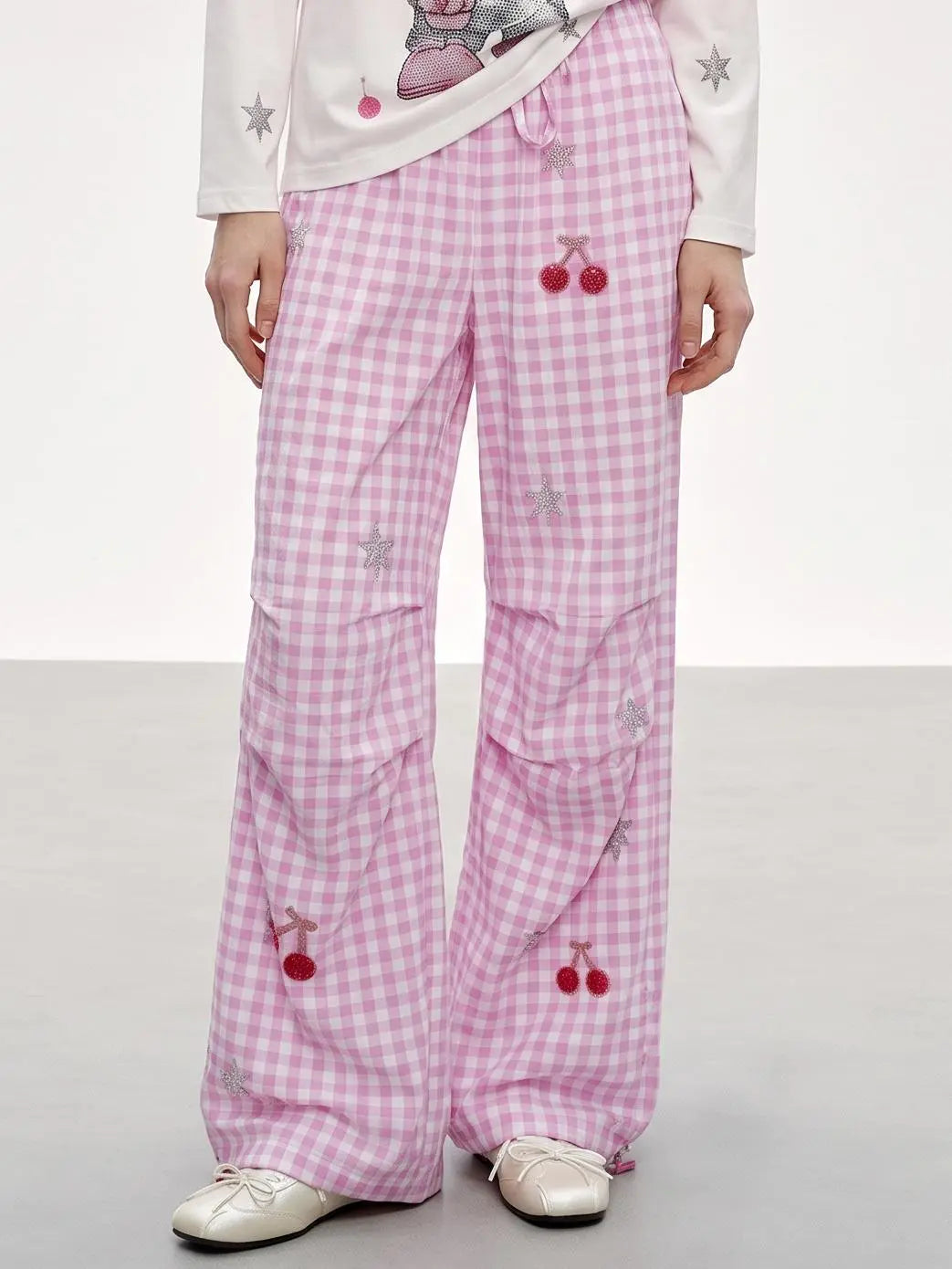 Pink and white gingham wide-leg pants with cherry and star embroidery, modeled with a white long-sleeve top and white sneakers. TCH Rhinestone Cherry Gingham Cargo Wide-Leg Pants