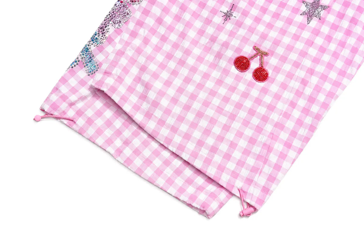 Pink and white gingham check fabric with sequined star and cherry embellishments, folded on a white background. TCH Rhinestone Cherry Gingham Cargo Wide-Leg Pants