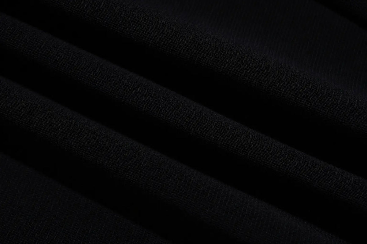 A close-up of dark black textured fabric with soft diagonal folds. TCH Rhinestone Constellation Straight-Leg Sweatpants