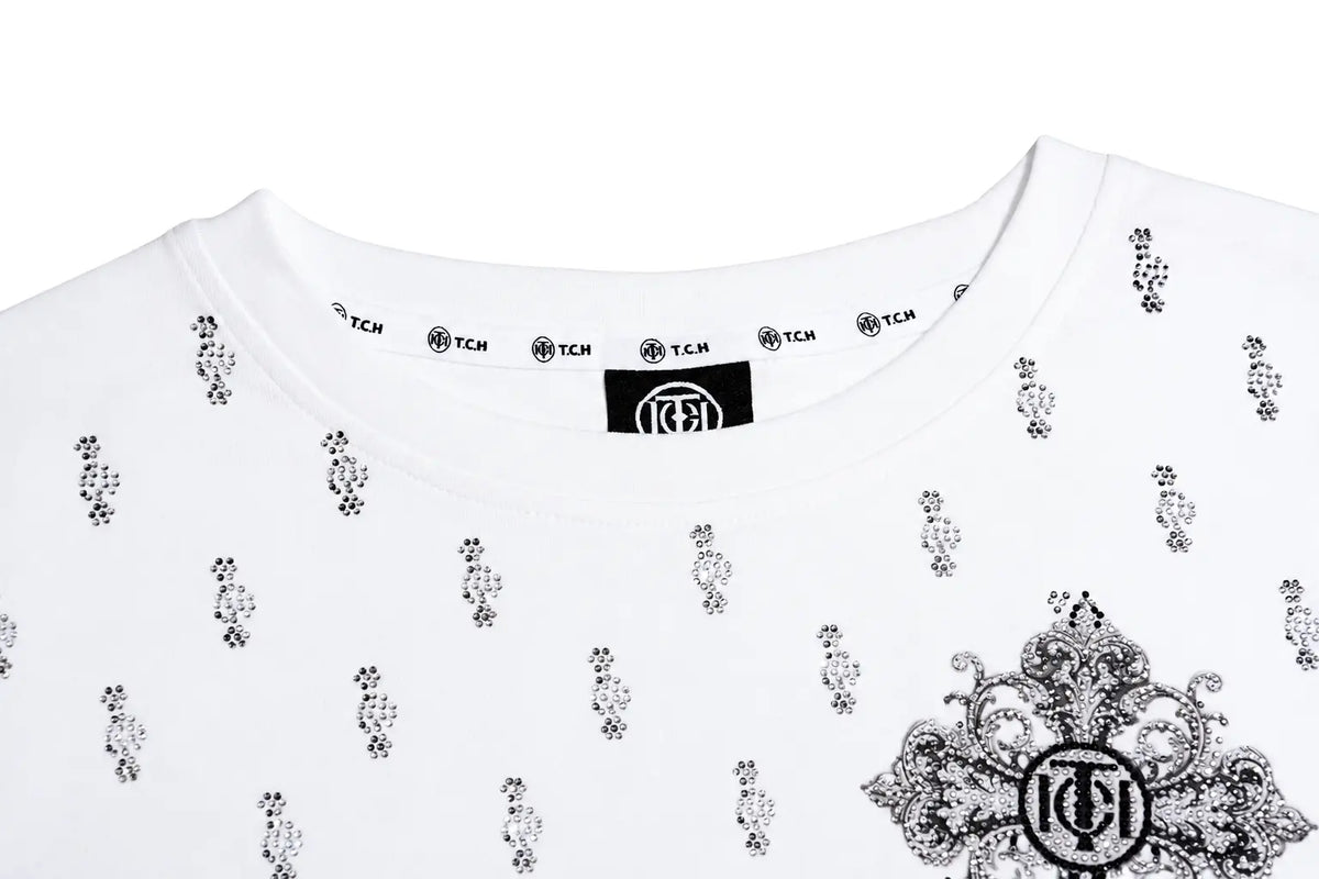 White crewneck t-shirt with black floral and ornate graphic prints, featuring a black neck label with the TCM logo. TCH Rhinestone Cross Graphic Fitted Long Sleeve Top