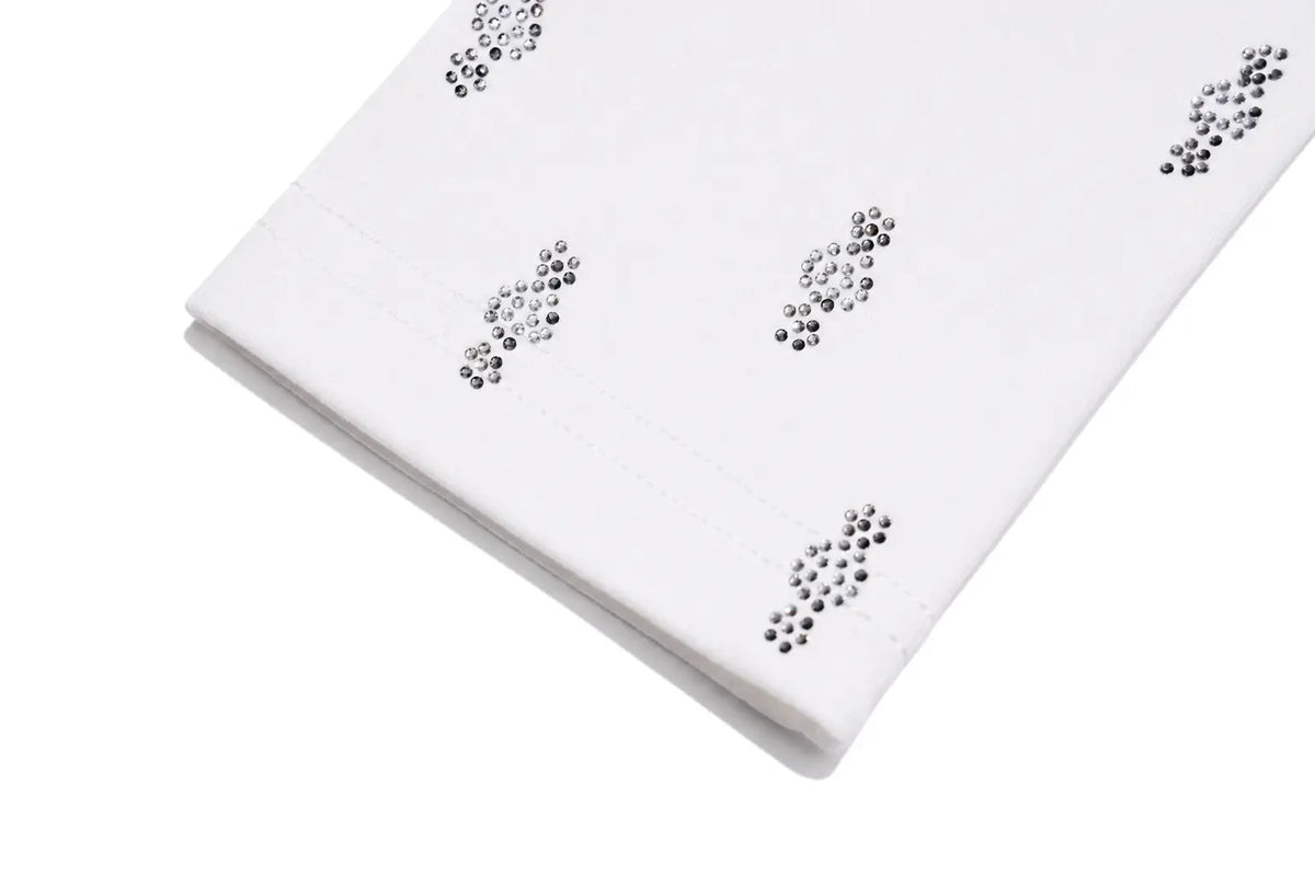 A folded white fabric item, likely a napkin or decorative cloth, embellished with small metallic silver rhinestone clusters arranged in a repeating pattern, shown on a clean white background. TCH Rhinestone Cross Graphic Fitted Long Sleeve Top