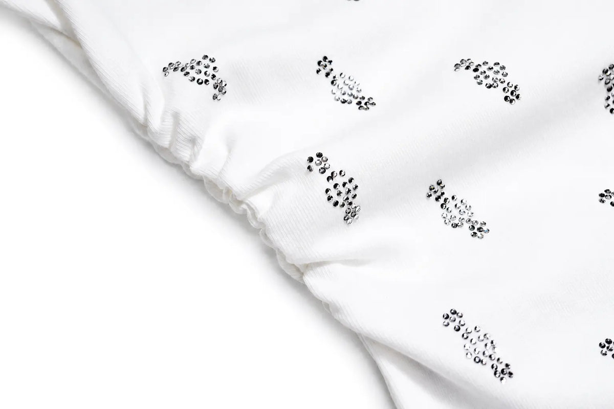 White fabric with a black dotted abstract pattern and a gathered elastic edge, shown in a close-up studio shot. TCH Rhinestone Cross Graphic Fitted Long Sleeve Top