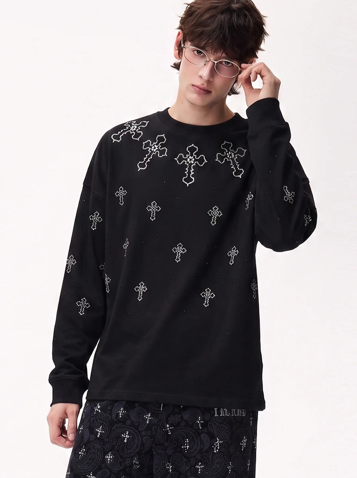 A model wearing a light blue denim jacket with various embroidered patches, including a teddy bear on the left chest and cherries on the sleeve, styled over a white t-shirt and dark pants. TCH Rhinestone Cross Pattern Black Long Sleeve T-Shirt