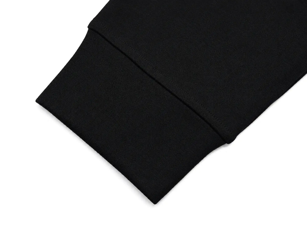 Close-up of a black fabric cuff with a neat hem, shown on a plain white background. TCH Rhinestone Cross Pattern Black Long Sleeve T-Shirt