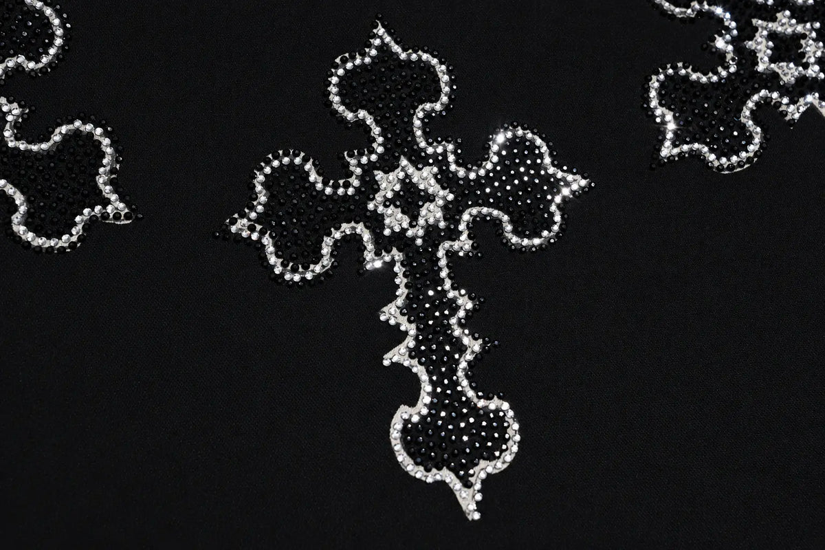 A close-up of a black fabric featuring a decorative cross applique embellished with silver rhinestones and crystals. TCH Rhinestone Cross Pattern Black Long Sleeve T-Shirt