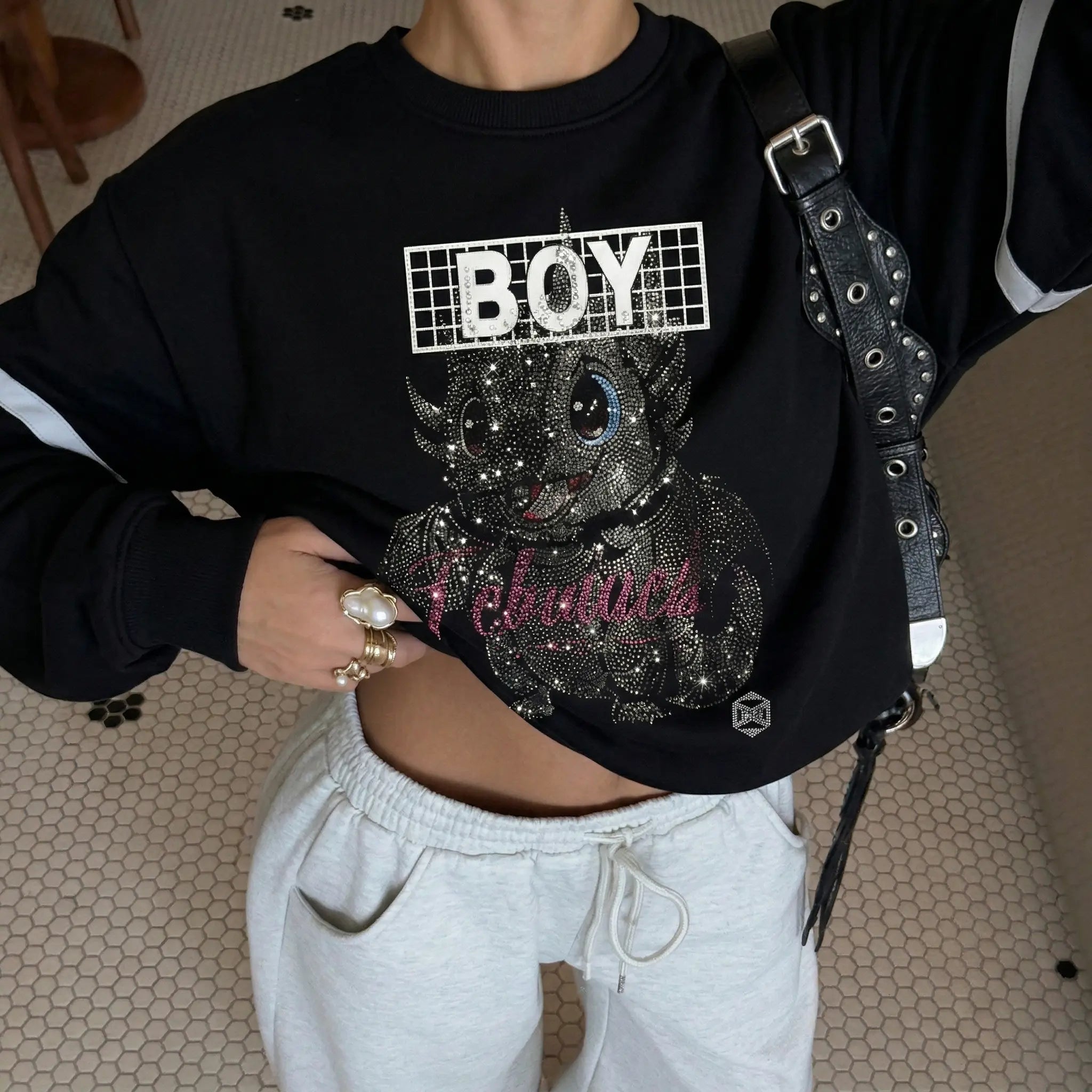 Person wearing a black sweatshirt with a graphic design and text, standing indoors. TCH Rhinestone Cute Dragon Sweatshirt-
