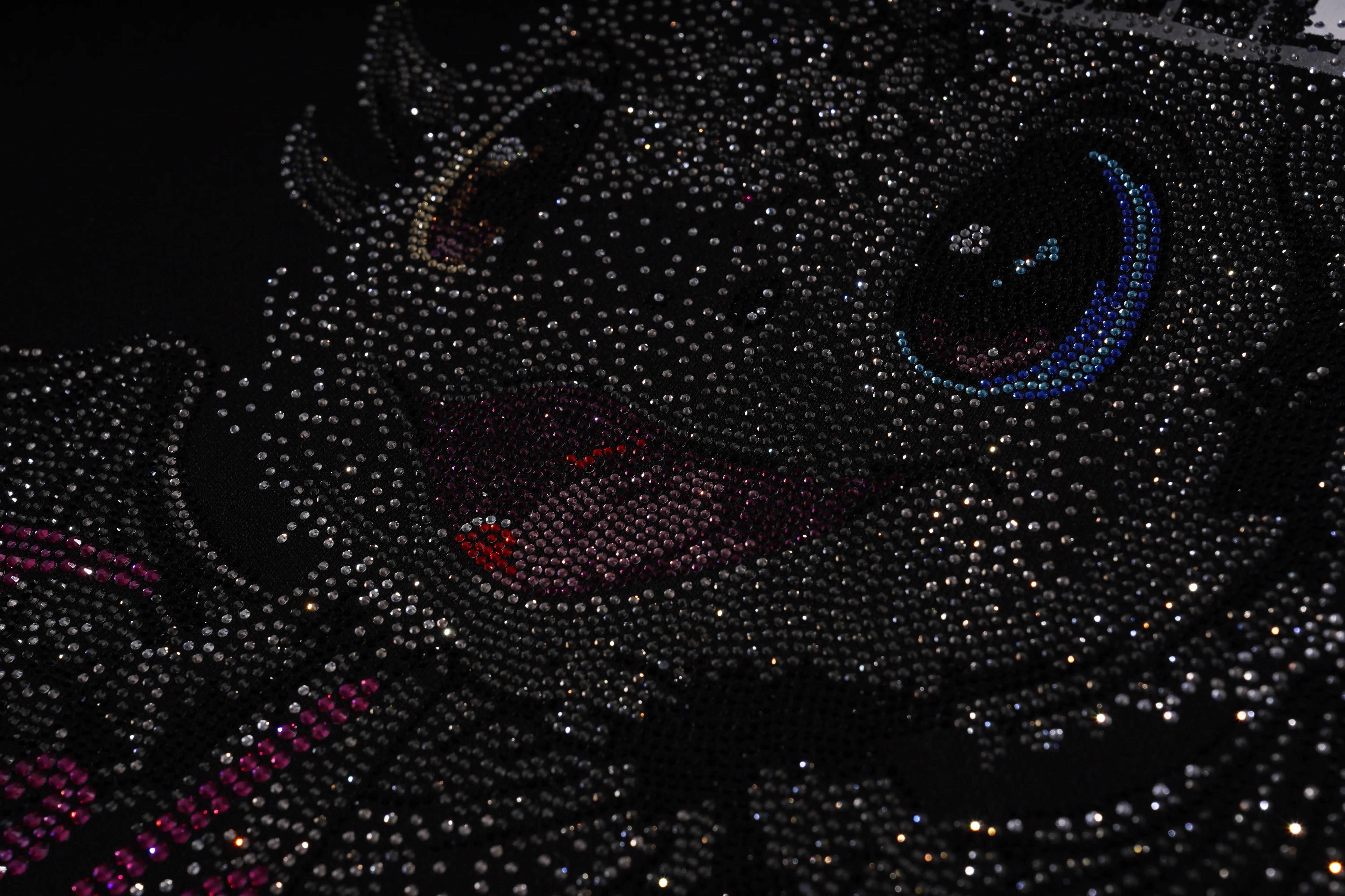 Close-up of a black cat figurine covered in rhinestones on a dark background
