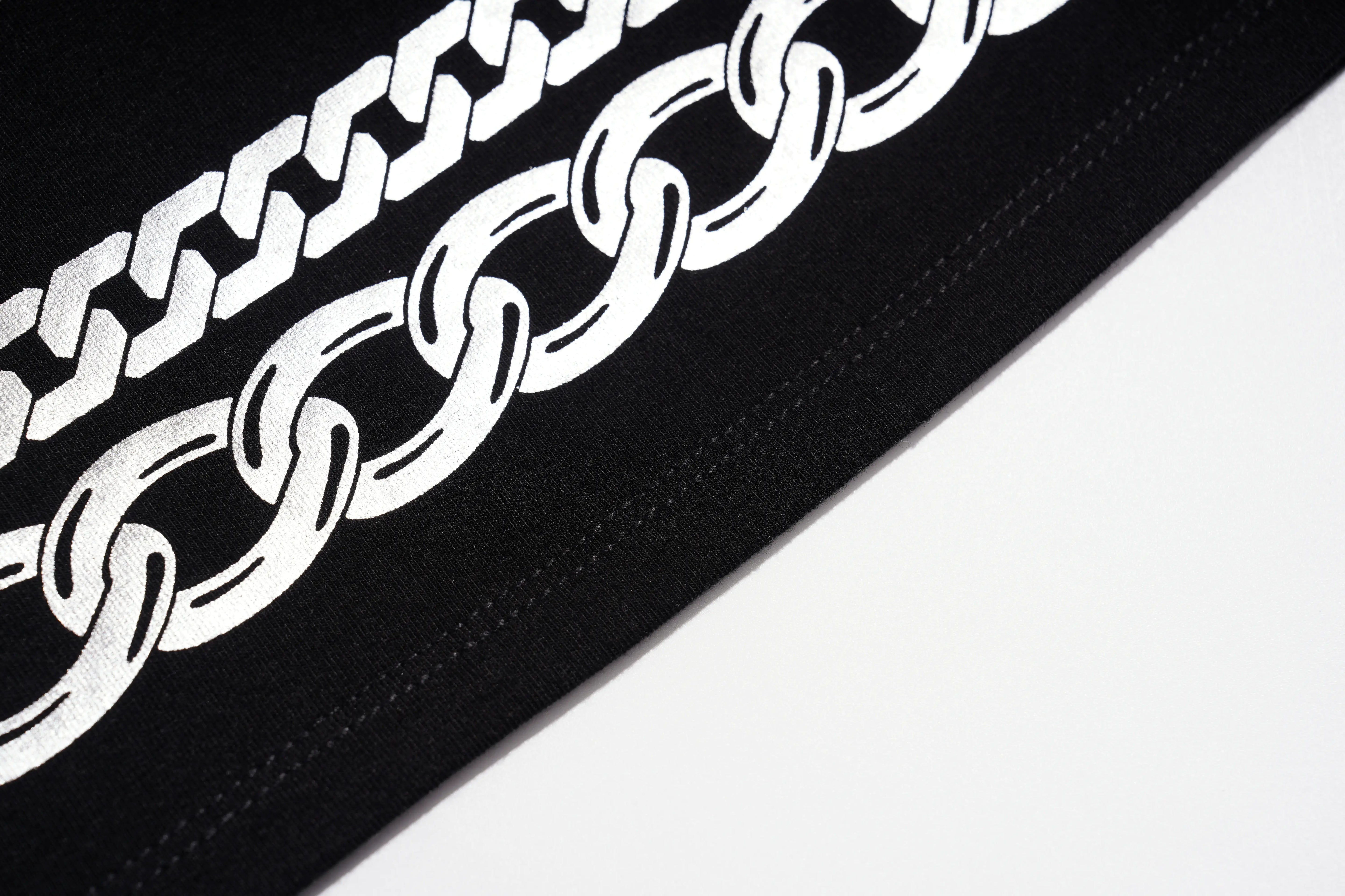 A close-up of a black fabric product featuring a bold white chain-link graphic printed diagonally across the surface. TCH Rhinestone Deer Graphic Mesh Sleeve Black Streetwear T-Shirt