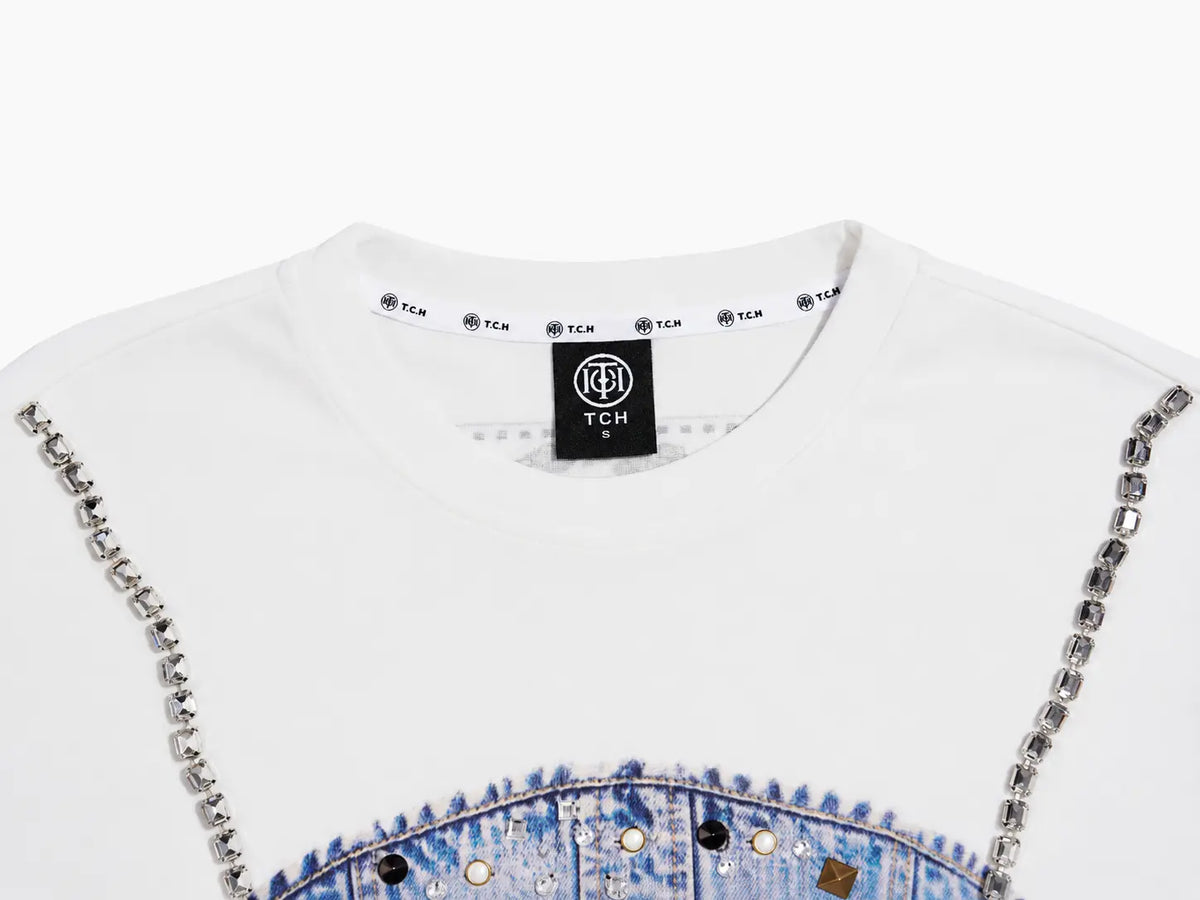 Close-up of a white TCH crewneck sweatshirt featuring a blue denim graphic at the bottom and silver rhinestone chain embellishments along the shoulders, on a white background. TCH Rhinestone Denim Corset Graphic Long Sleeve T-Shirt