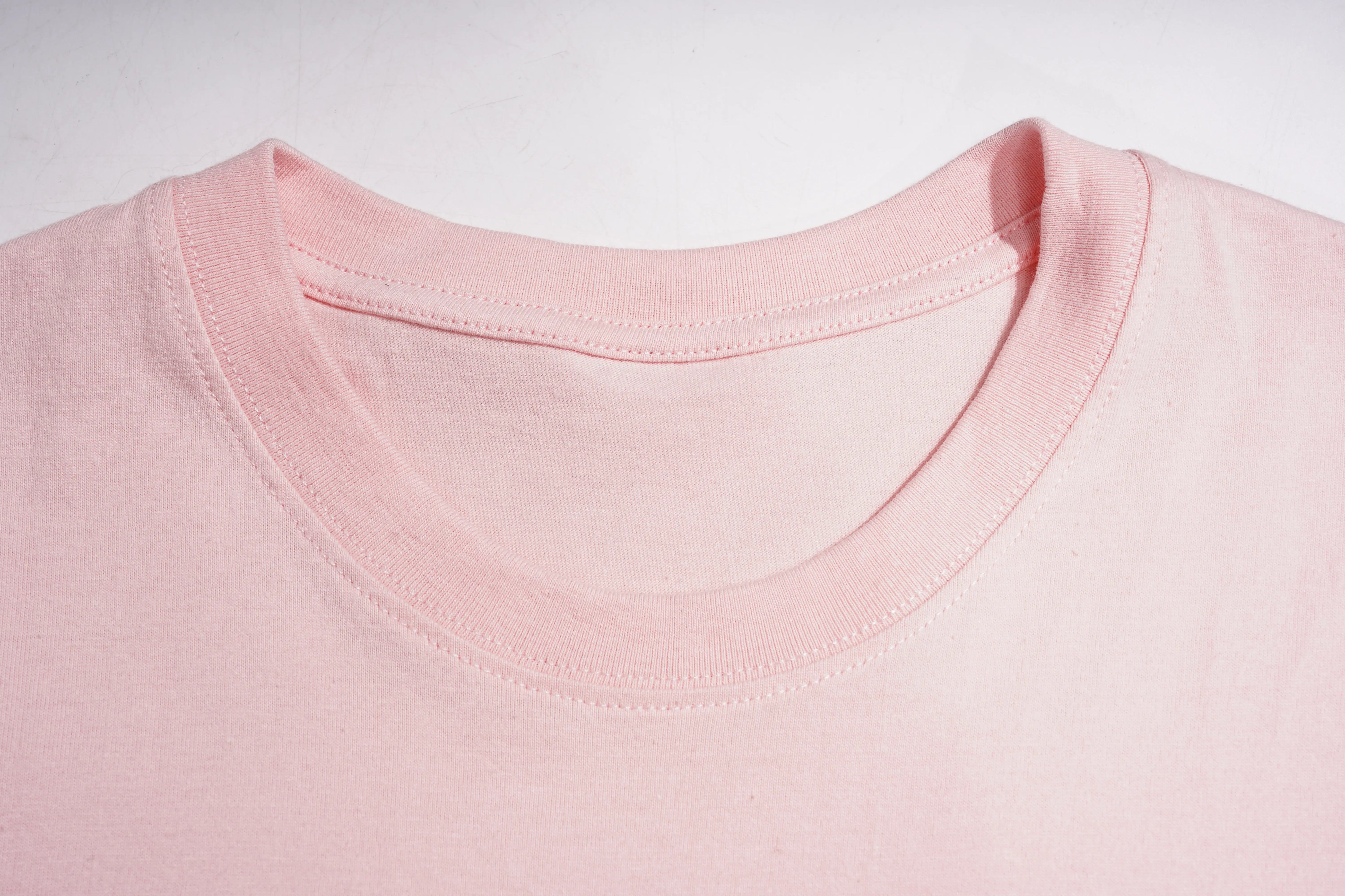 Close-up of a light pink crew-neck t-shirt showing the ribbed collar and stitching details against a white background. TCH Rhinestone Double Bow Cotton T-Shirt