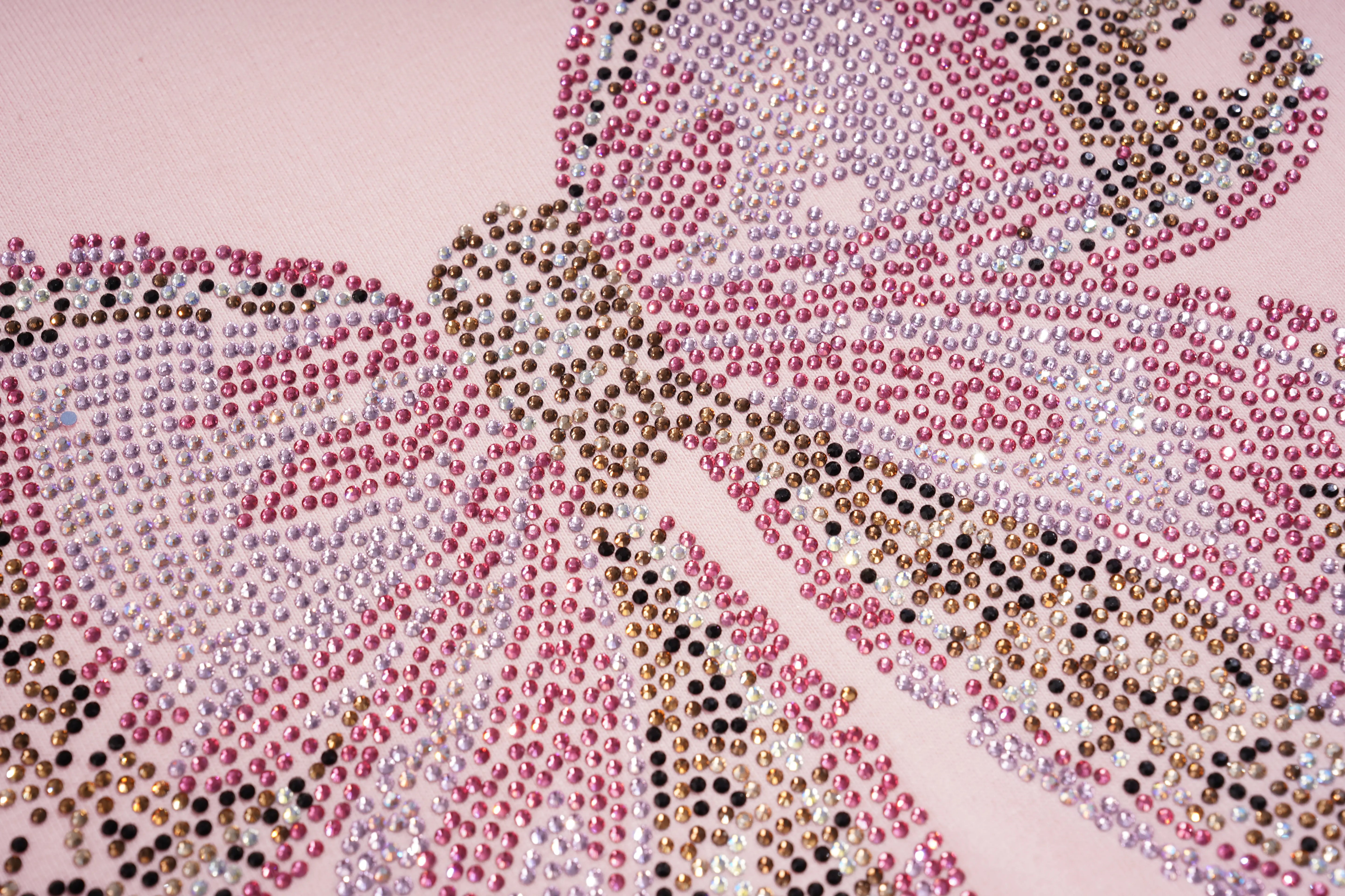A close-up of a butterfly design made from many small rhinestones on a pale pink background. The butterfly uses pink, silver, white, and dark metallic rhinestones. TCH Rhinestone Double Bow Cotton T-Shirt