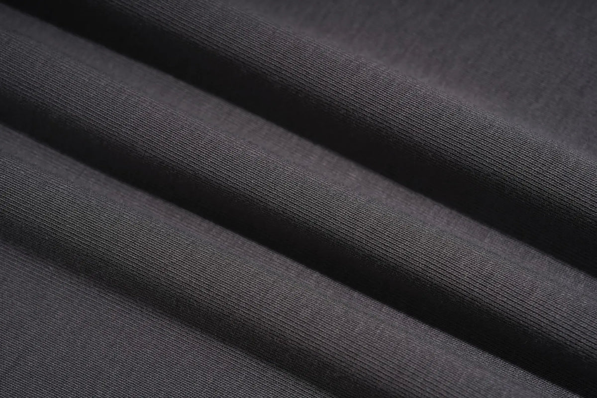 Close-up of dark charcoal gray ribbed fabric with soft diagonal folds showing the knit texture. TCH Rhinestone Fantasy Unicorn Graphic Long Sleeve T-Shirt