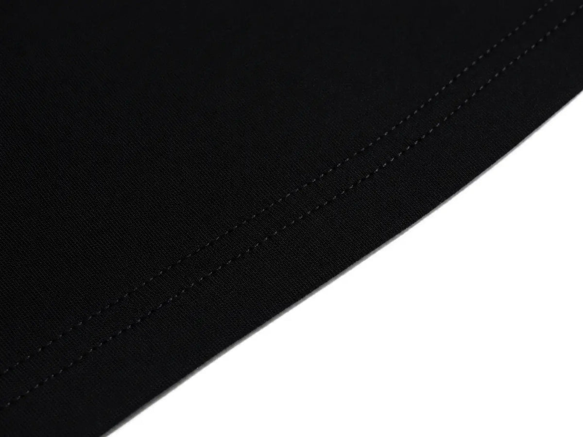 Close-up of a black fabric surface with a visible stitched edge against a white background. TCH Rhinestone Fleur-de-Lis Fitted Long Sleeve Top