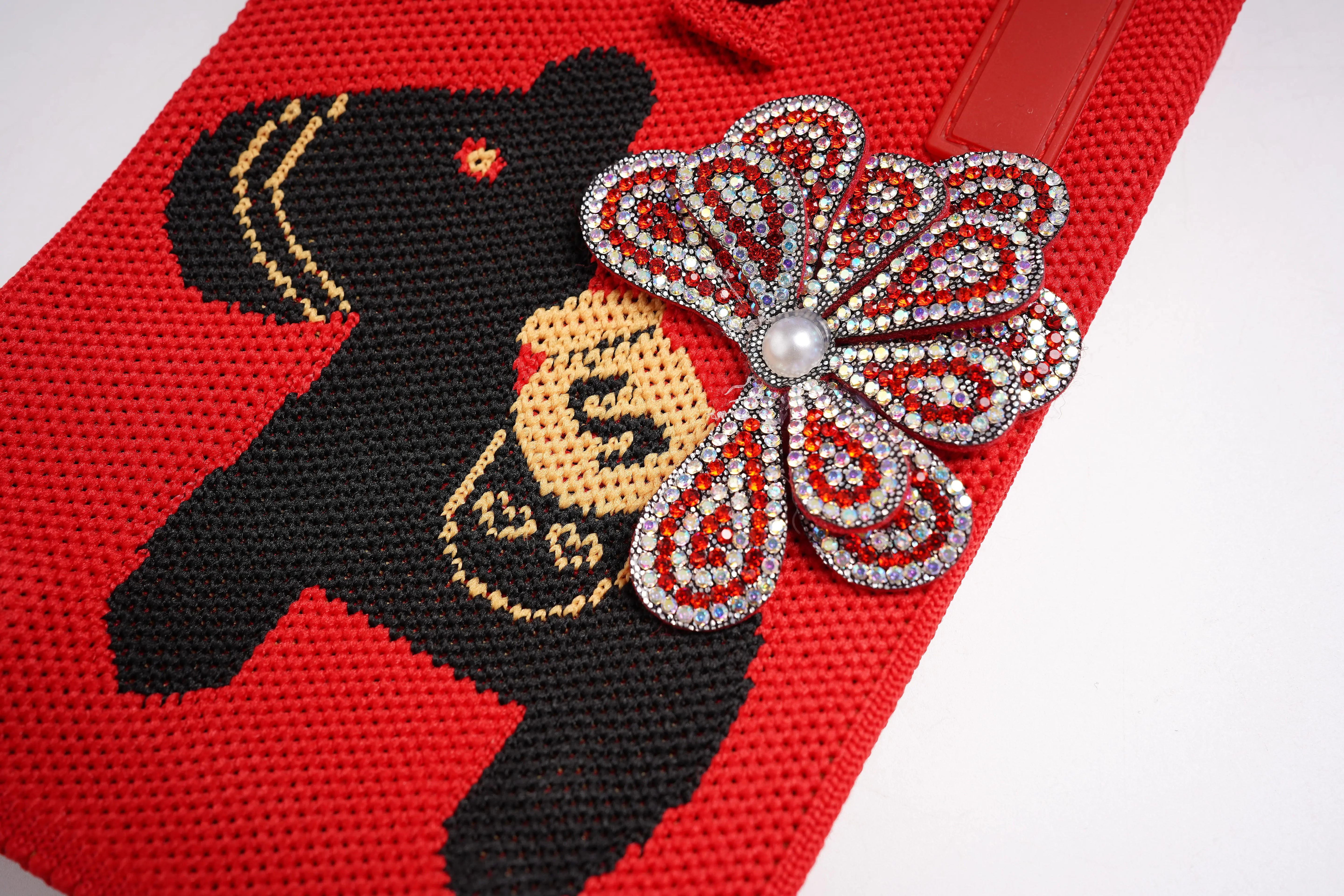 Red fabric with black silhouette of a person and decorative butterfly brooch. TCH Rhinestone Floral Black Horse Red Crossbody & Handbag