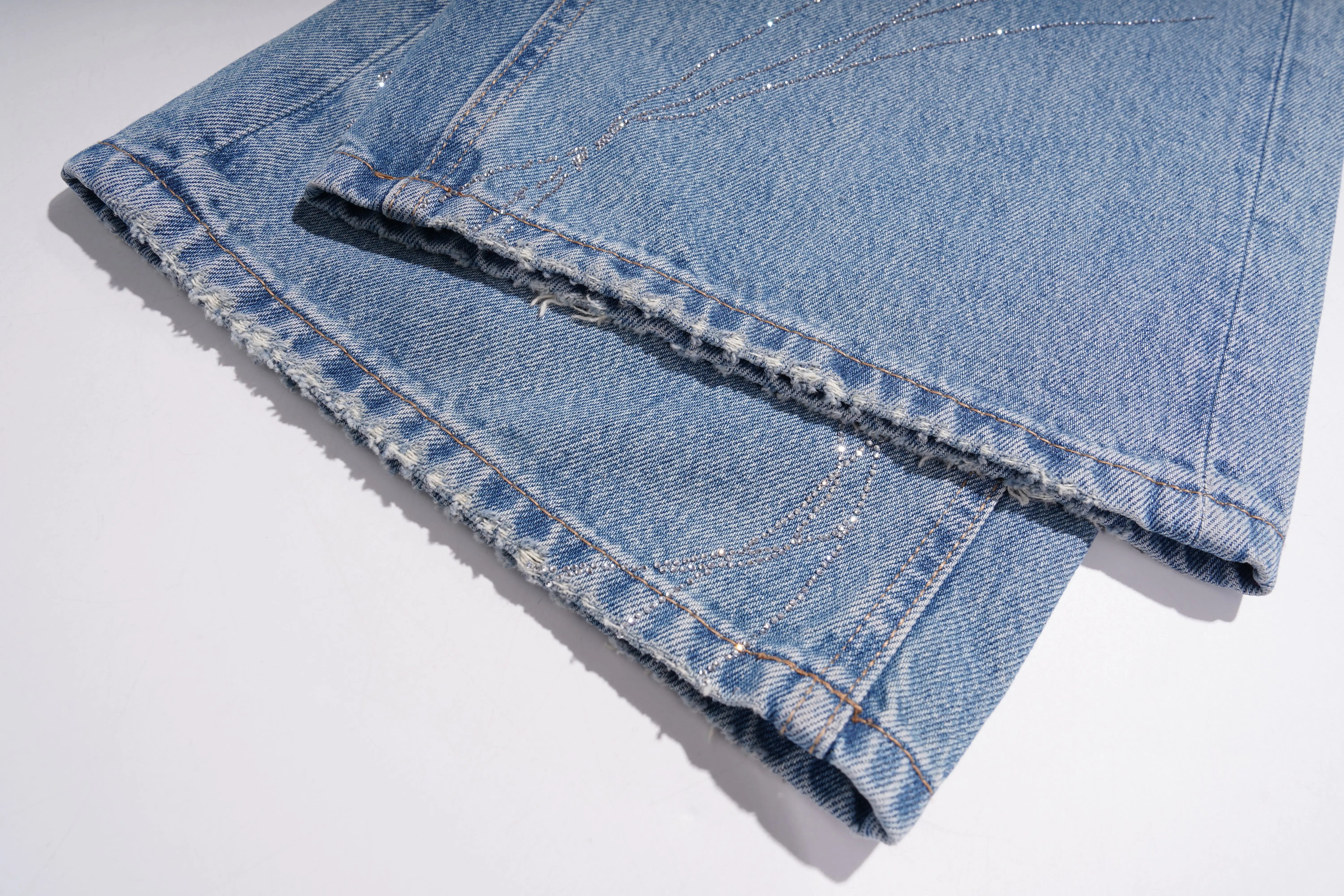 Folded blue denim jeans on a white background, TCH Rhinestone Floral Wide-Leg Blue Jeans