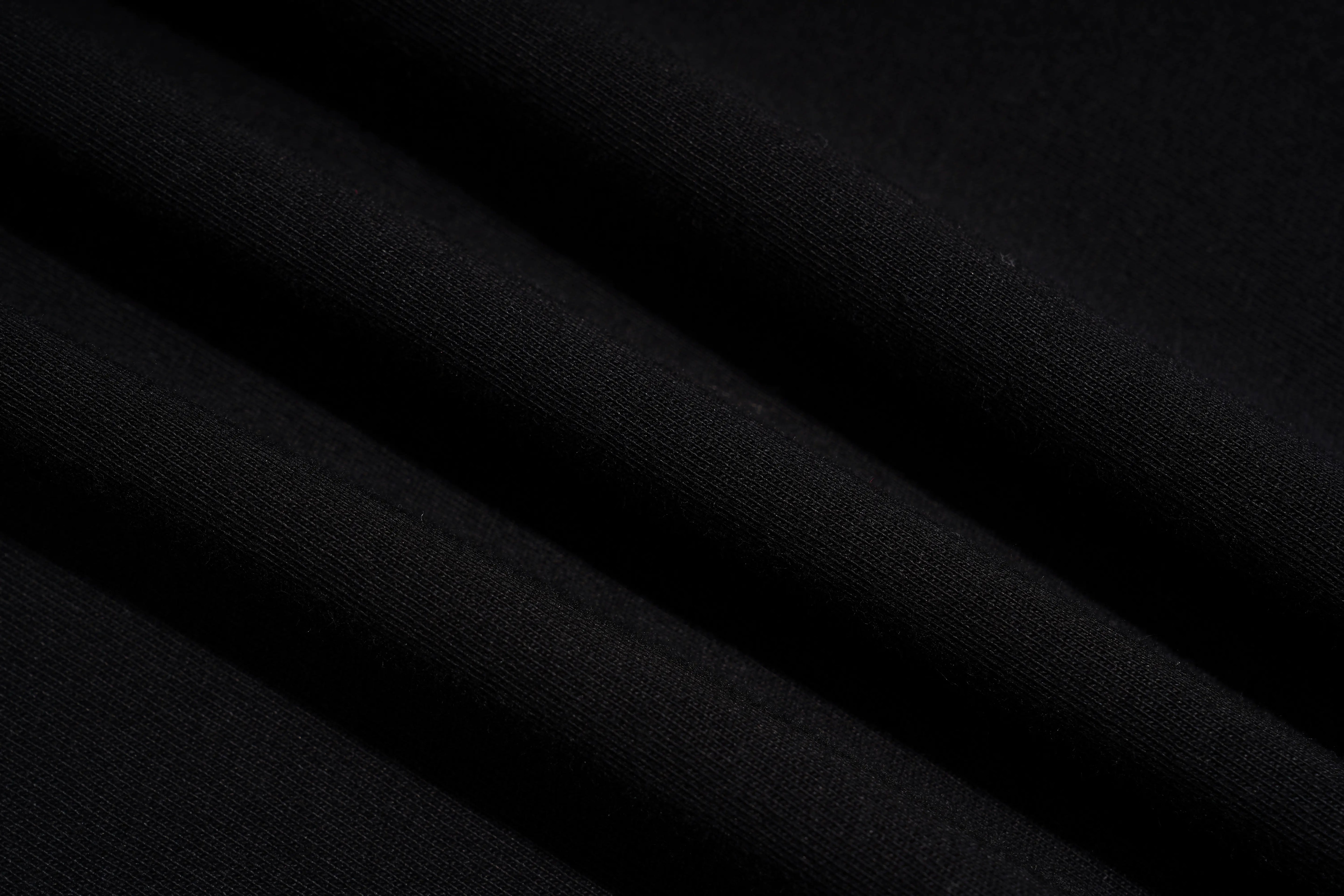 A close-up of draped black fabric with soft diagonal folds showing a fine knit texture. TCH Rhinestone Floral Wing Techno Graphic T-Shirt