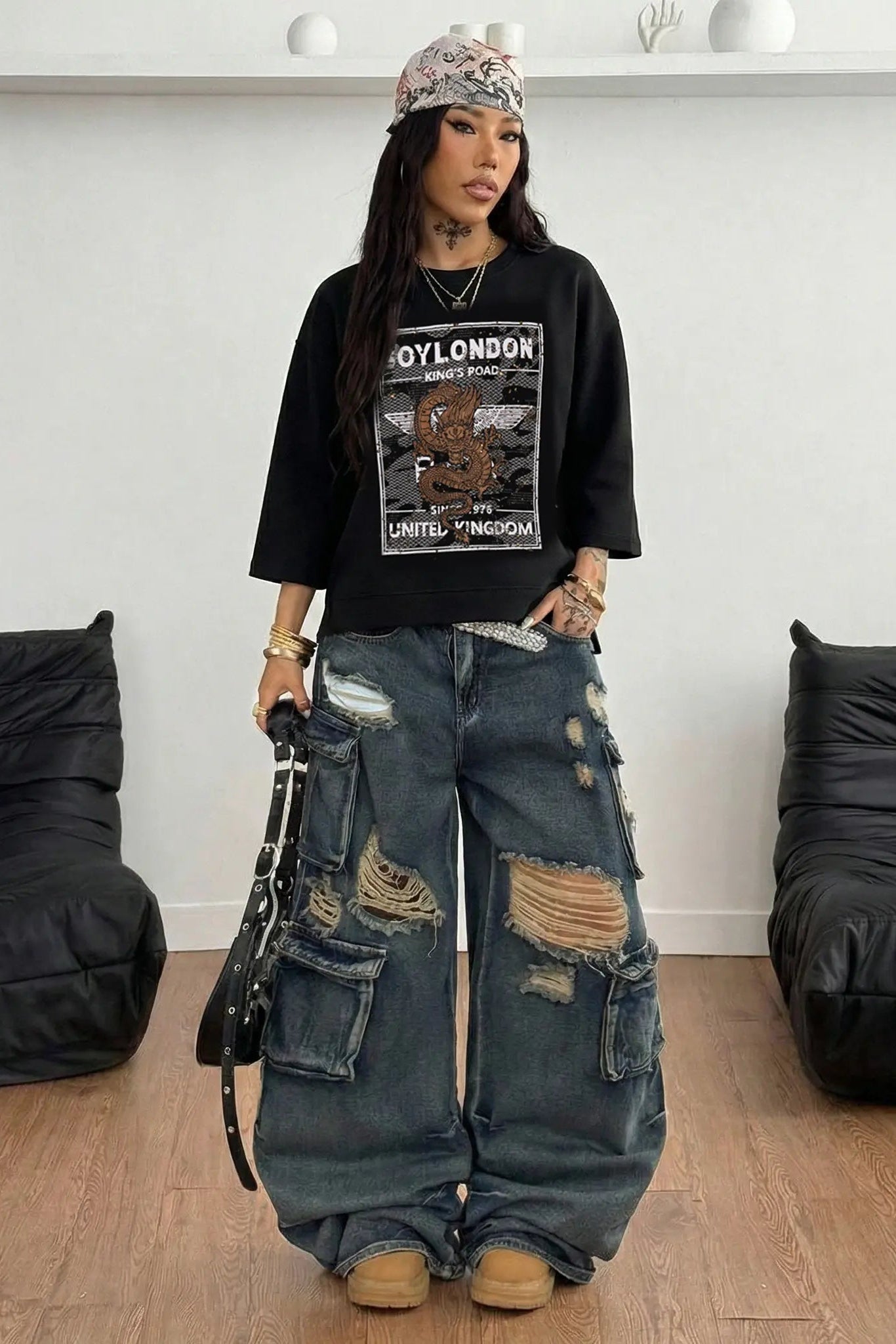 Person wearing a black graphic t-shirt and ripped jeans in a room with black bean bags. TCH Rhinestone Gold Dragon Poster Sweatshirt