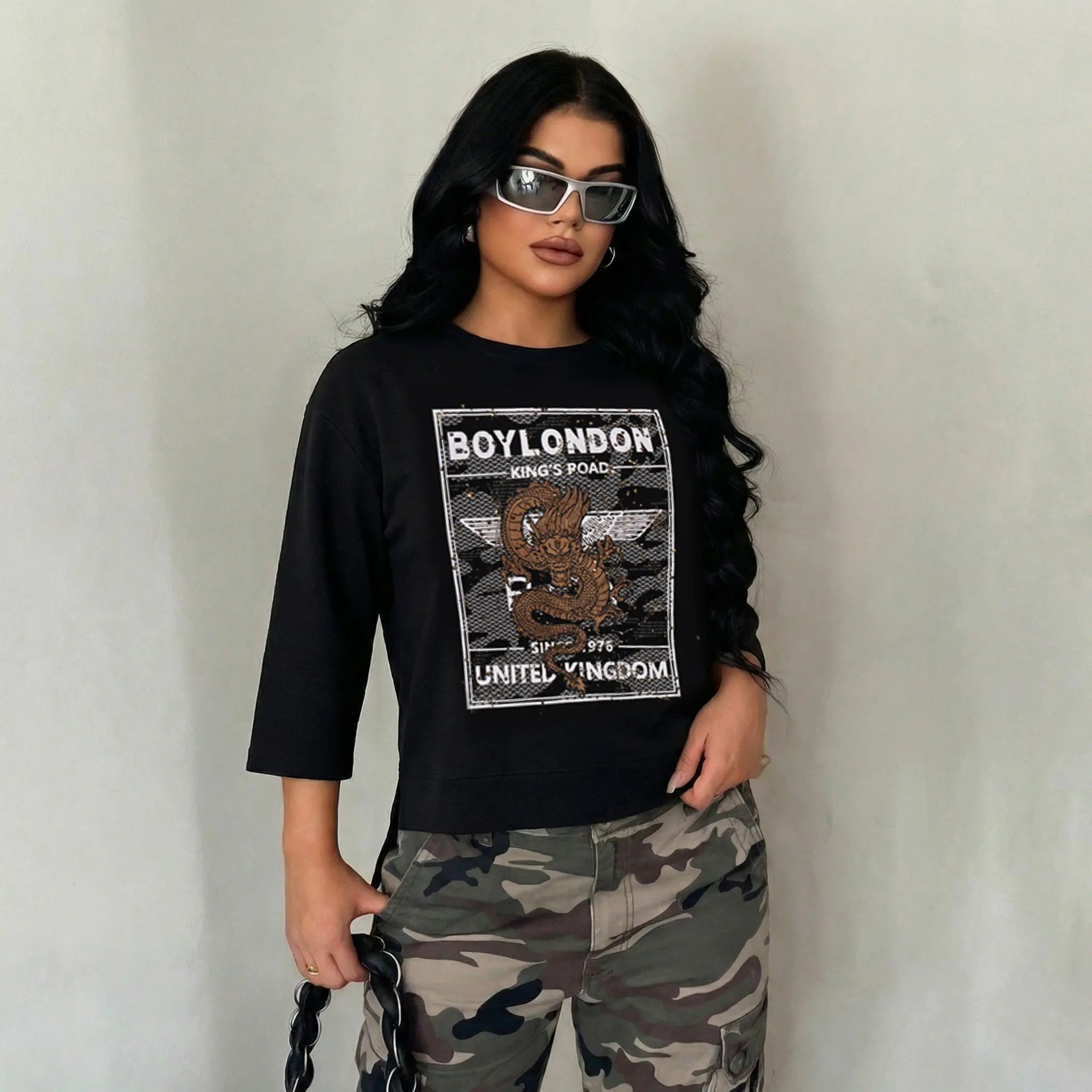 Person wearing a black t-shirt with 'BOYLONDON' design and camouflage pants against a plain background, TCH Rhinestone Gold Dragon Poster Sweatshirt