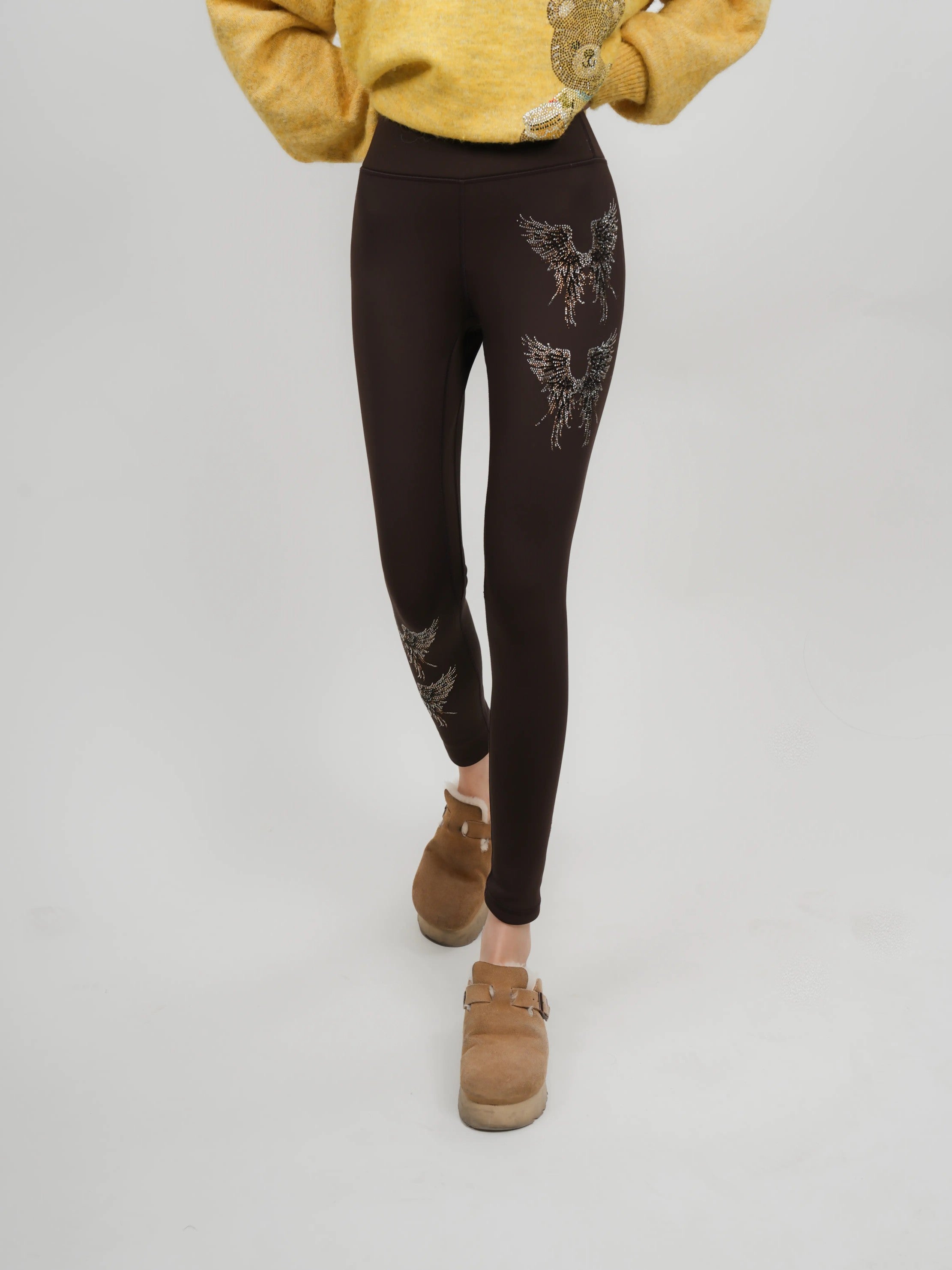 Person wearing black leggings with floral patterns on a plain background, TCH Rhinestone Golden Wings Black High-Waist Leggings