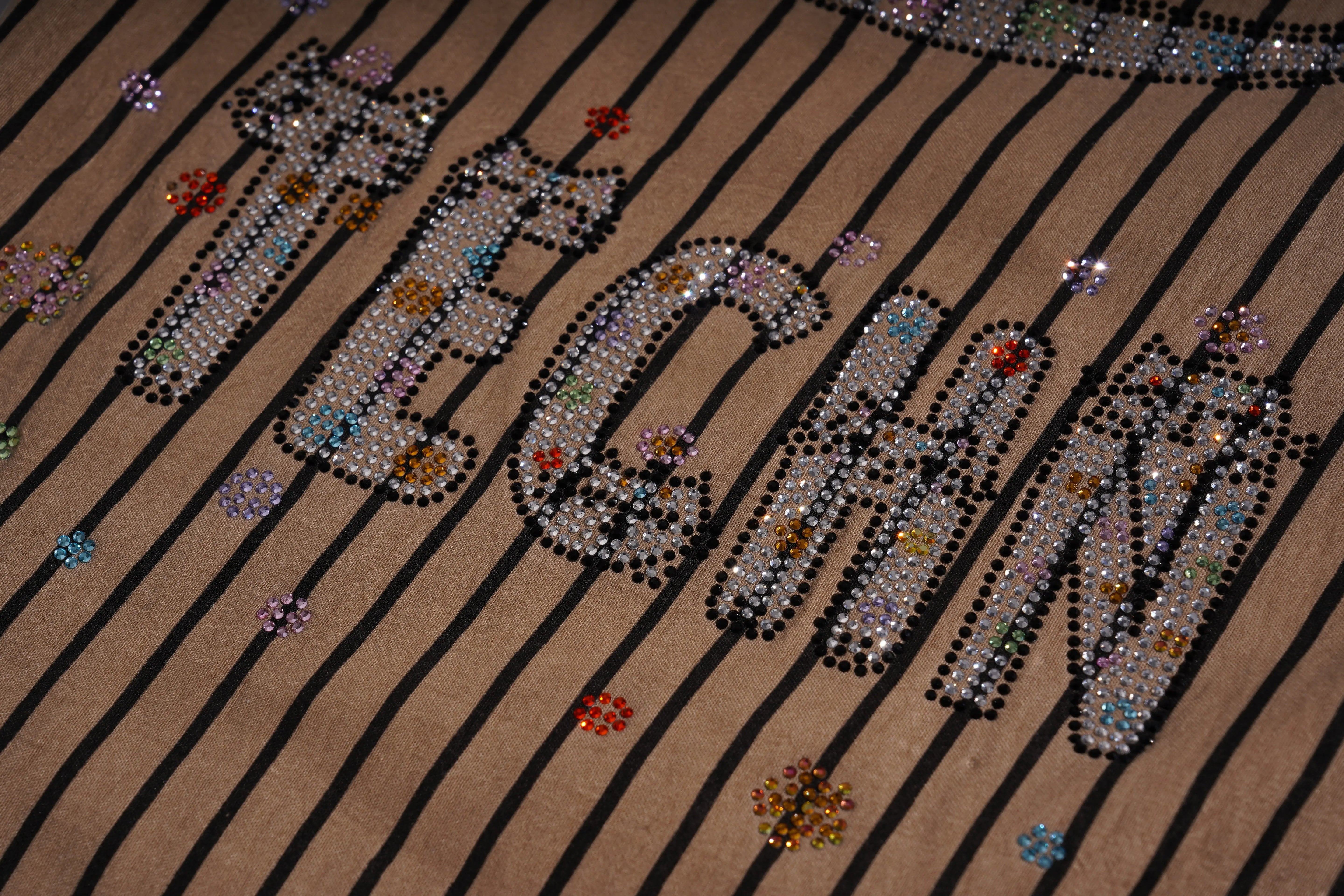 Text 'Megan' spelled out with rhinestones on a striped background, TCH Rhinestone Graffiti Cat & Cherry Set