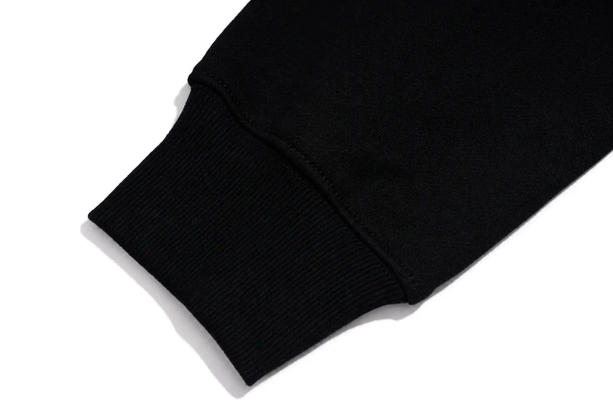 Close-up of a black ribbed knit sleeve cuff on a white background. TCH Rhinestone Graphic Black Crewneck Sweatshirt