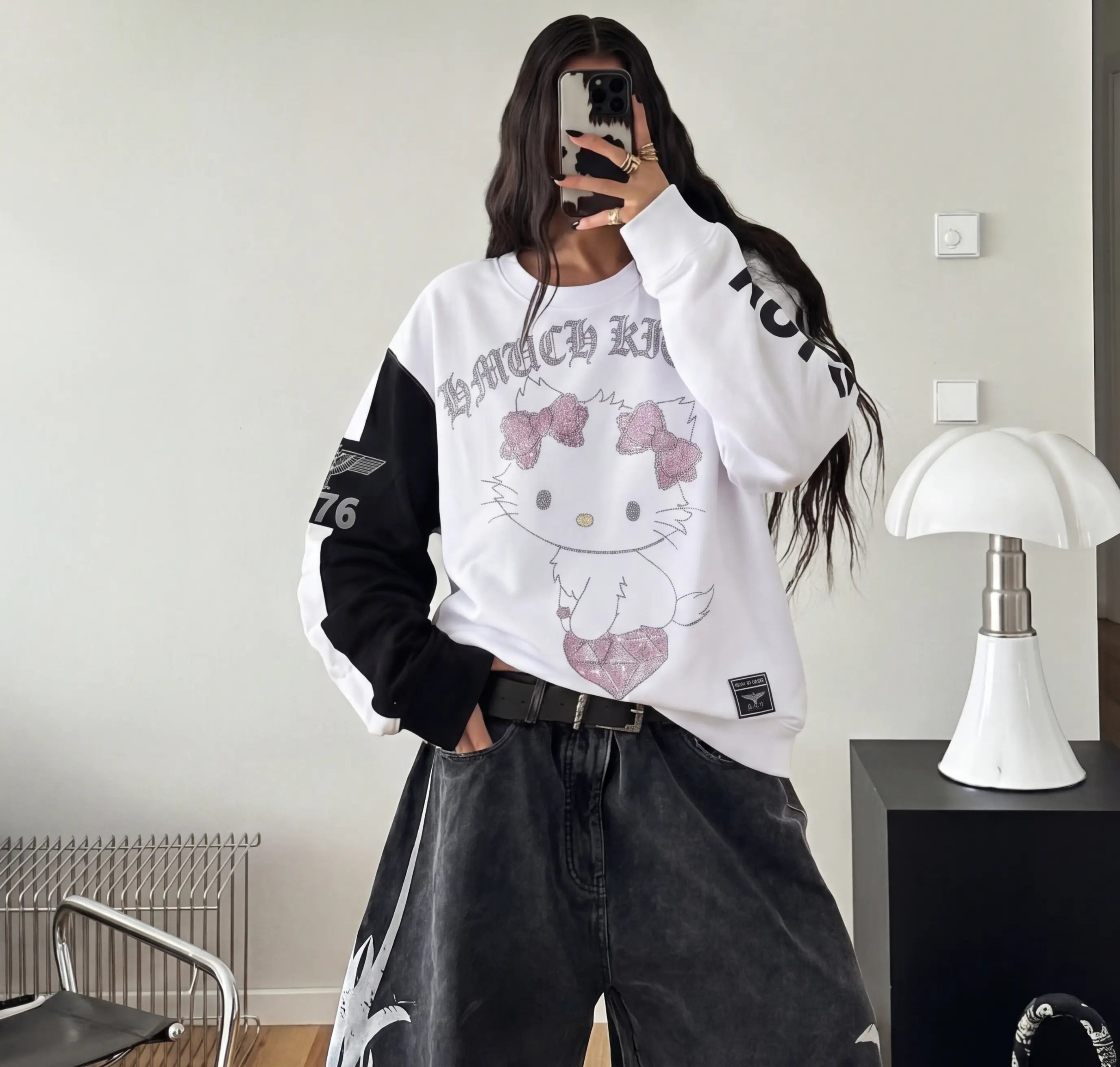 Person wearing a white oversized sweatshirt with a cartoon character design, standing in a room. TCH Rhinestone Hello Kitty BOYLONDON Sweatshirt