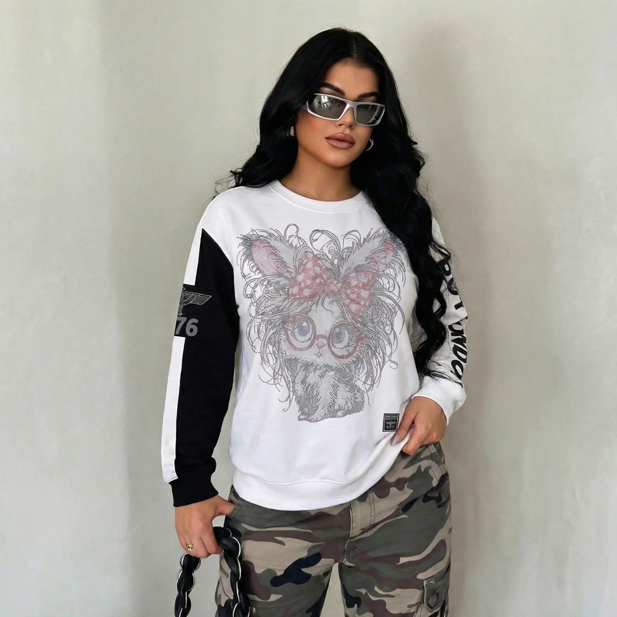 Woman wearing a white sweatshirt with a graphic design and camouflage pants against a plain background, TCH Rhinestone Hello Kitty BOYLONDON Sweatshirt